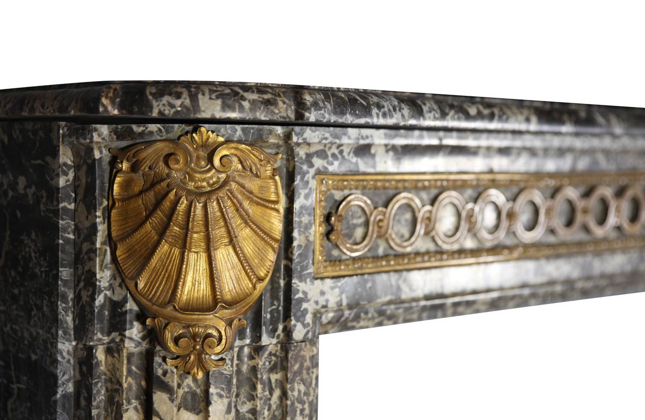 Ein hochmoderner antiker Mantel aus Marmor Gris St-Anne aus der Übergangszeit Louis XVI, 18. 
Die Fassade und die Türpfosten sind mit den originalen Bijouterien aus Messing verziert. Dieser große Mantel ist in perfektem Zustand. Es stammt aus der