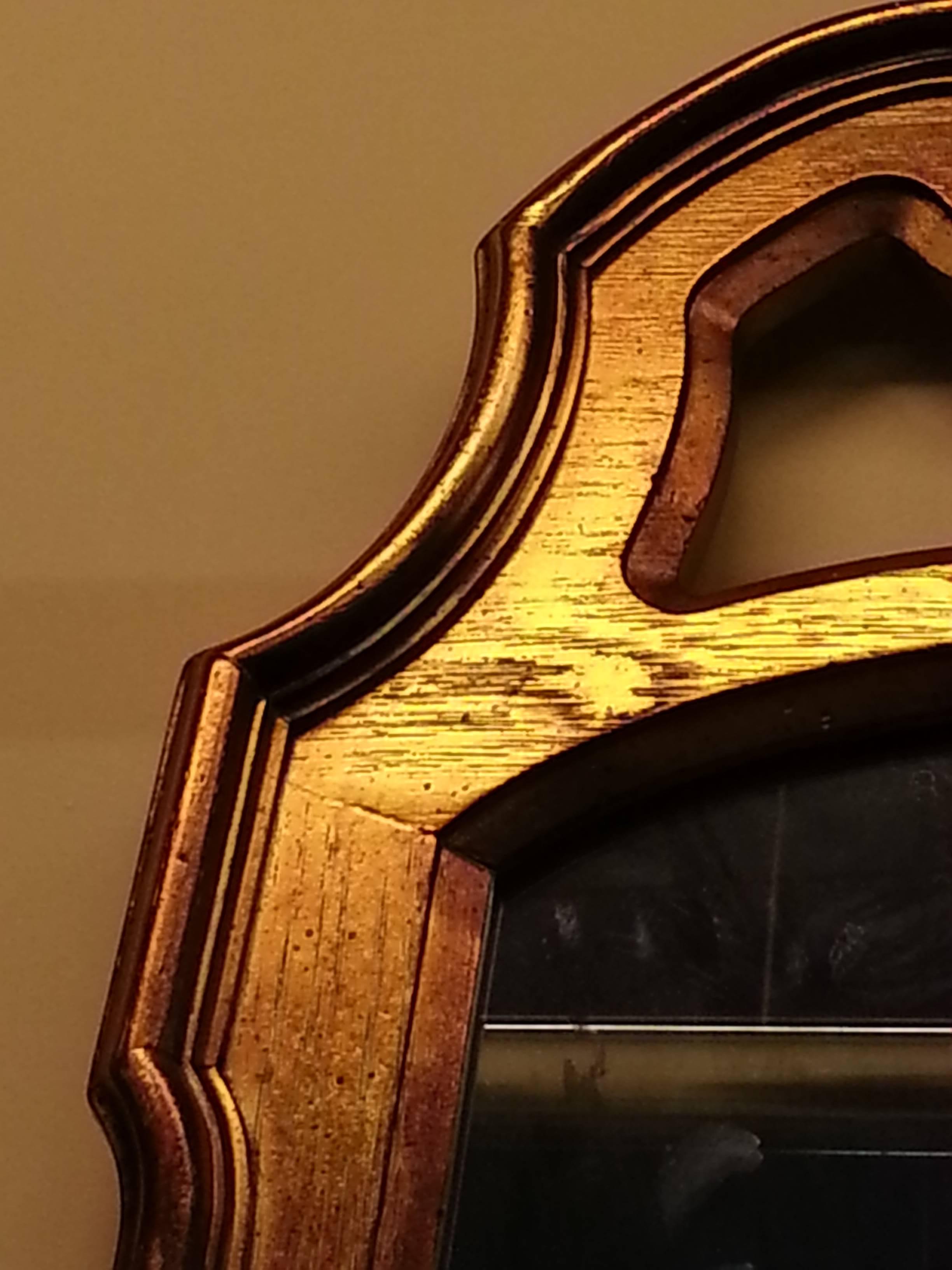 Beautiful midcentury wall mirror. Made by Drexel Heritage.  In the Hollywood Regency style. Gold in color and a French relief at the top forming a crown.