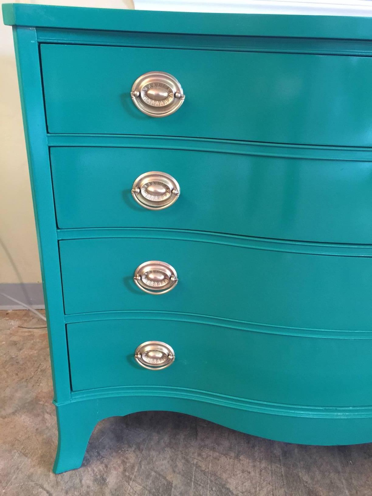 This stunner in Ming Jade lacquer with gilded pulls is solid mahogany made in the 1950s. With four ample drawers, it can provide storage in a foyer, a bedroom, or a dining room. Curvy lines make it sleek yet elegant.