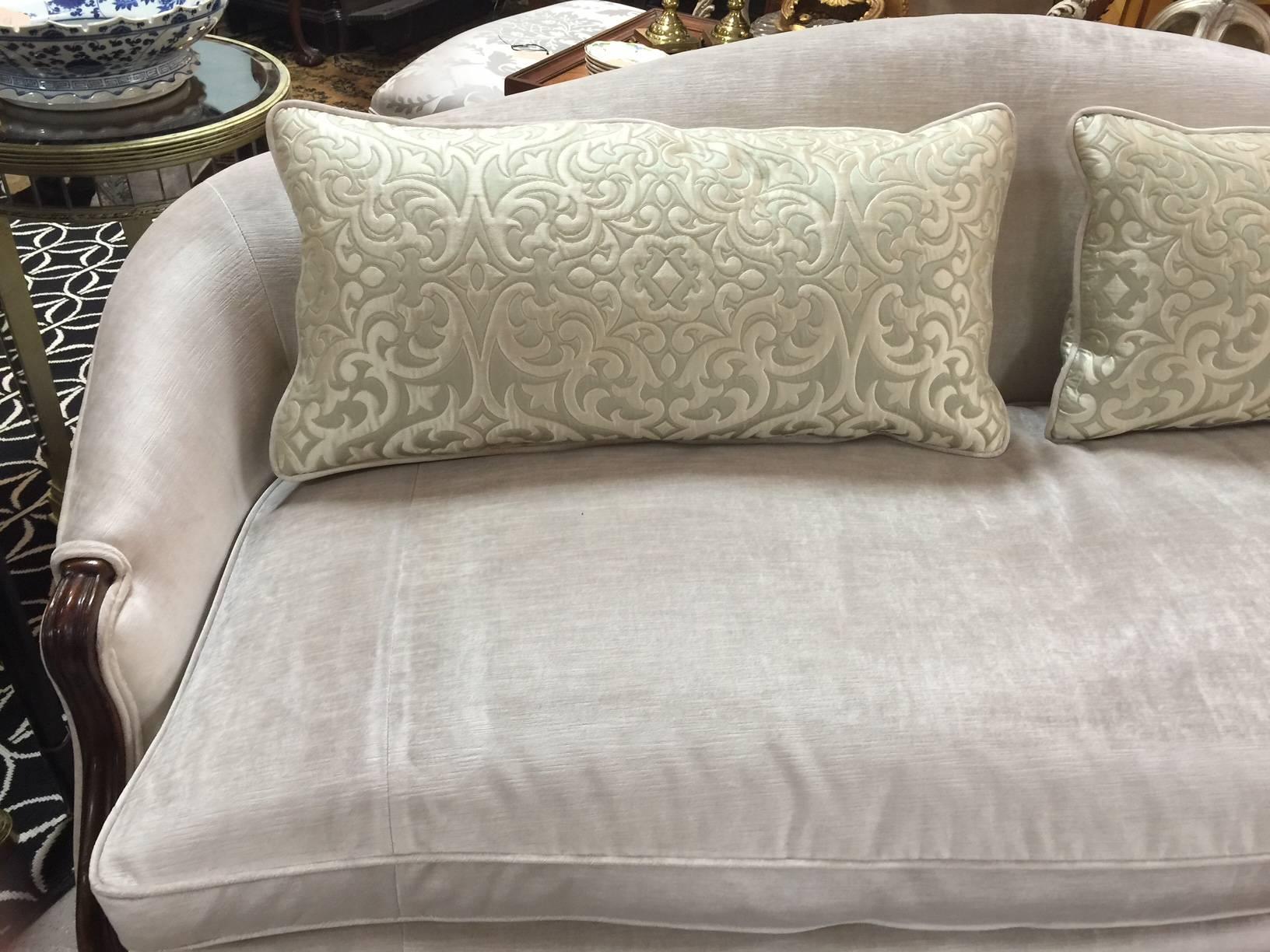 This sofa is newly upholstered in a soft creamy champagne color with coordinating lumbar pillows corded in velvet. The sofa has eight legs, simply carved, a single cushion, and down filled pillows, double piping detail.  Made by Drexel Heritage. 