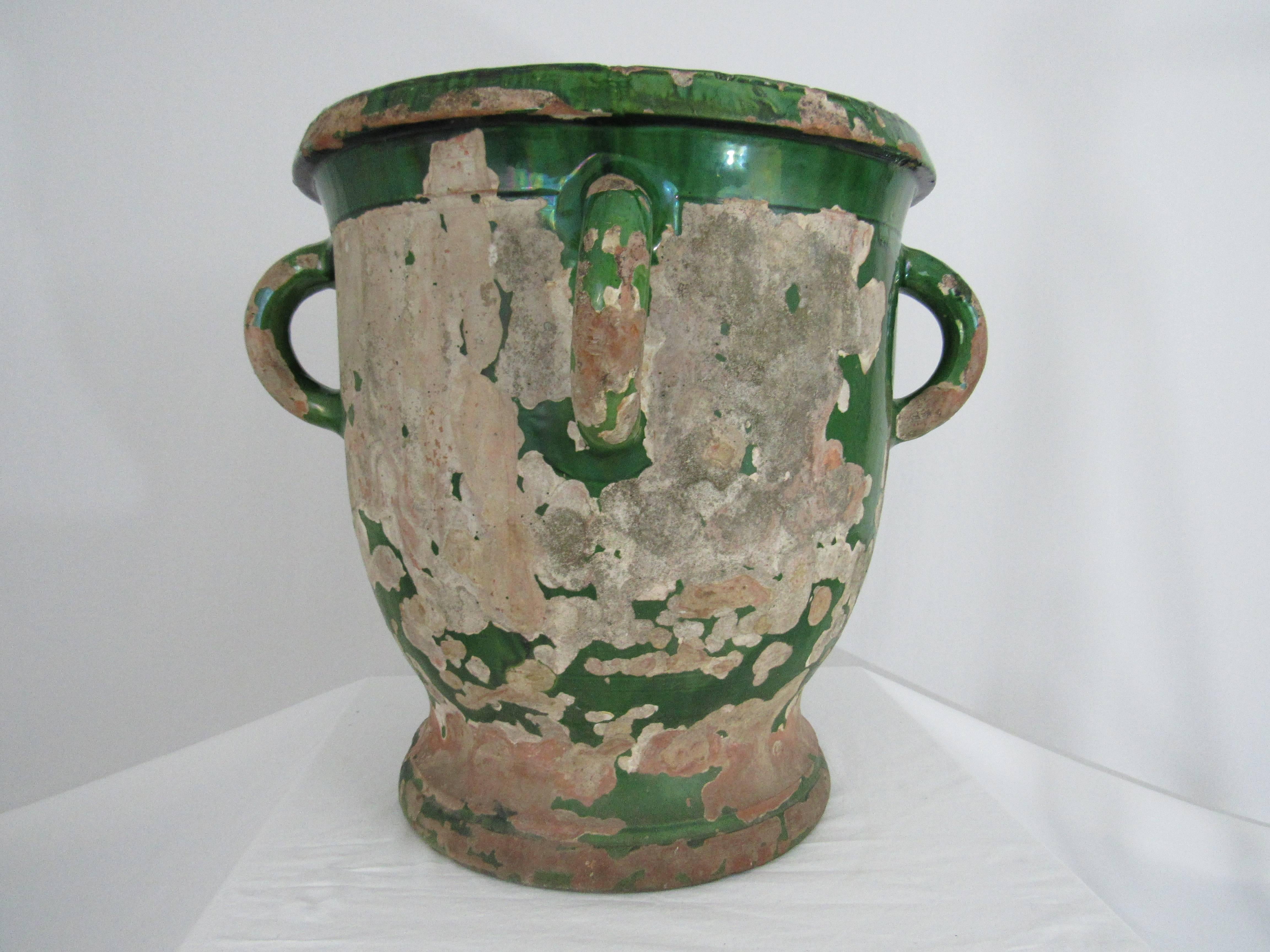 
A large boldly-scaled French emerald green glazed terra cotta garden urn from Anduze, France. The urn has a bell shape body with four handles and an everted lip. The inside of the urn is in excellent condition and ready for use in your garden.


