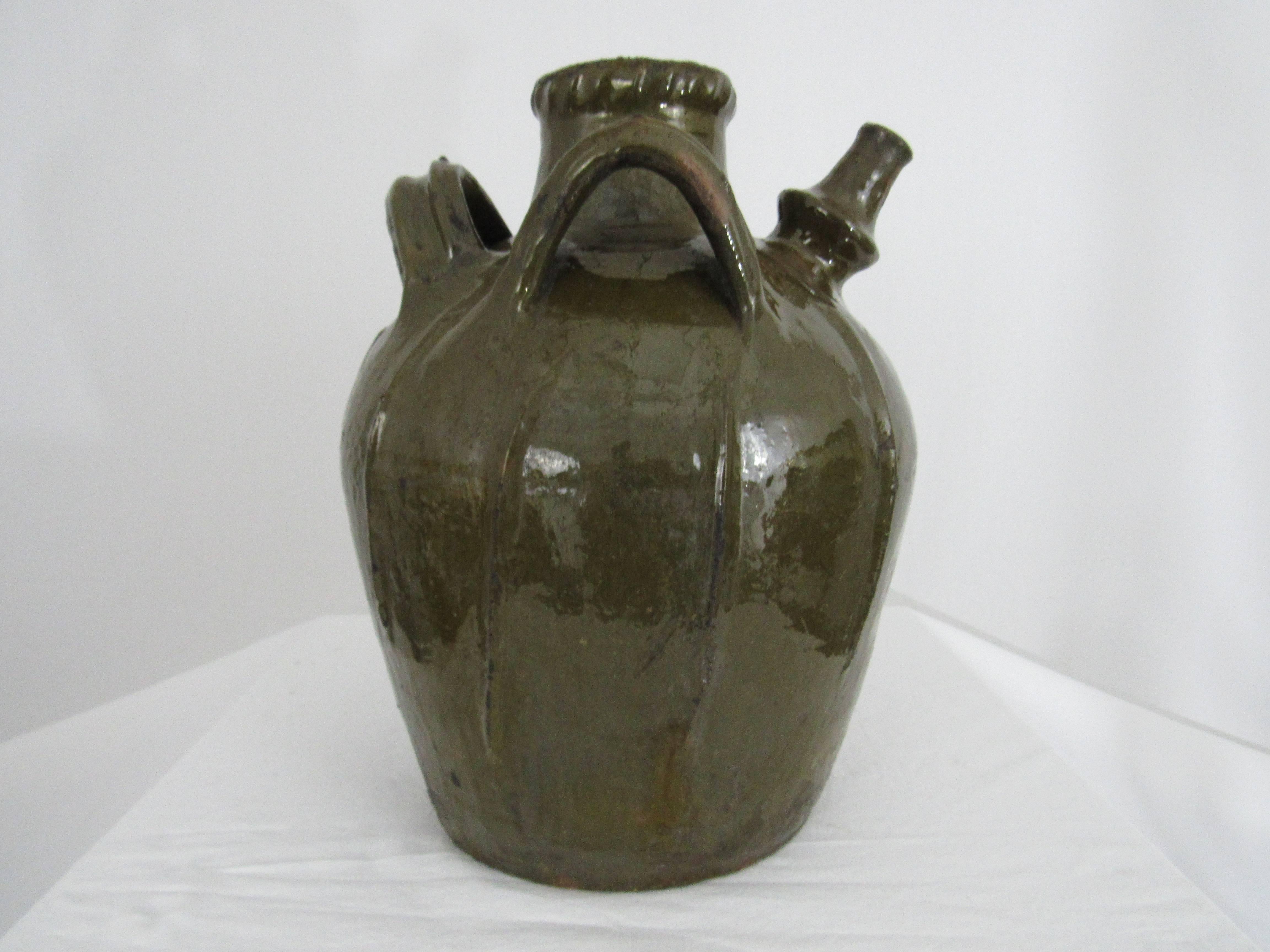 French oil jug from the Auvergne region in France. A large three-handled green-glazed terracotta storage vessel, with pouring spout. It has a wonderful green color that is characteristic of this region in France. The glaze as well as the jug is in