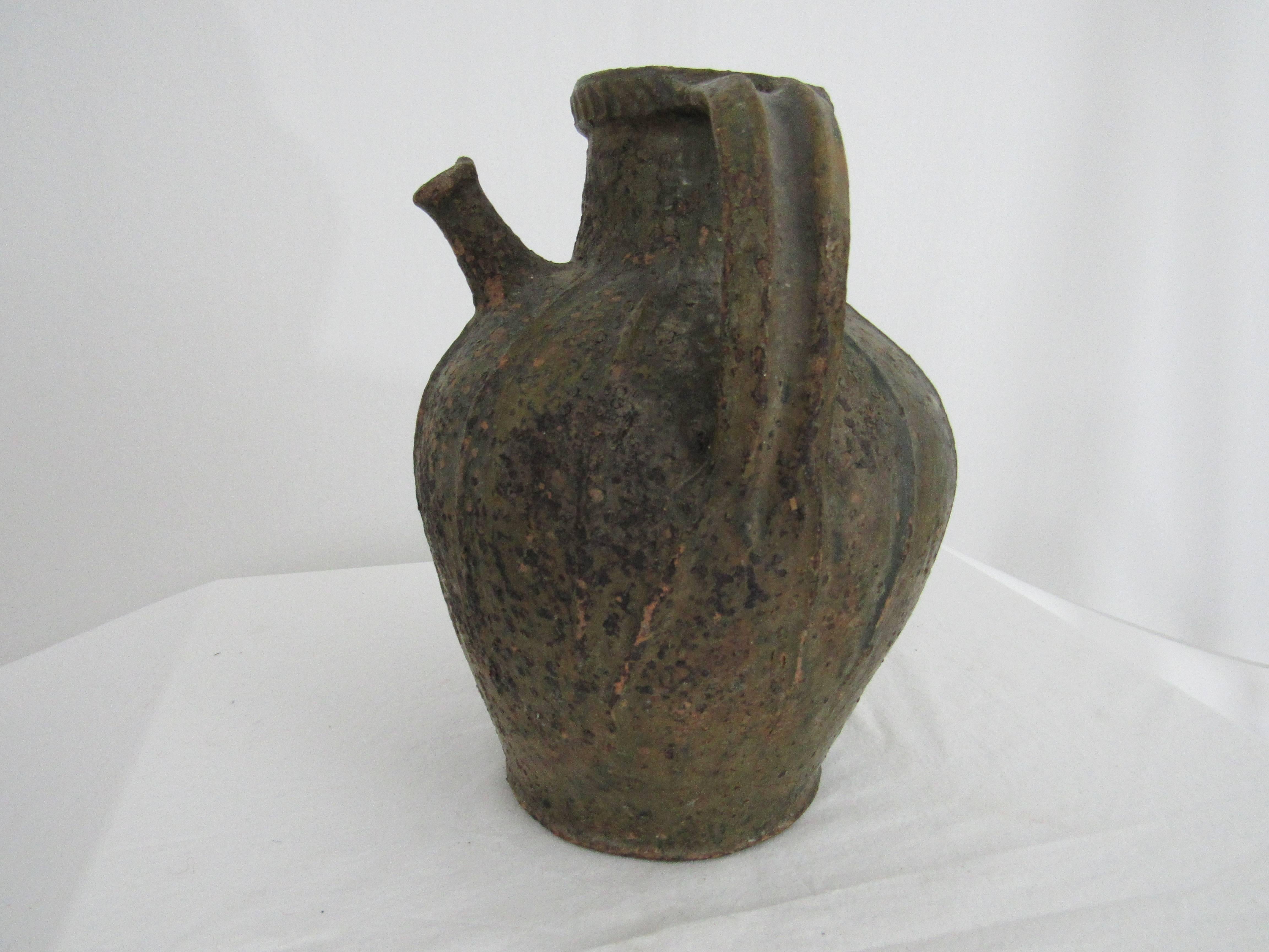 French oil jar from Auvergne region in France. A two-handled green-glazed terracotta storage vessel, with pouring spout. It has a wonderful textured surface as well as a spattering of dried olive oil left on the surface as an artifact of years of