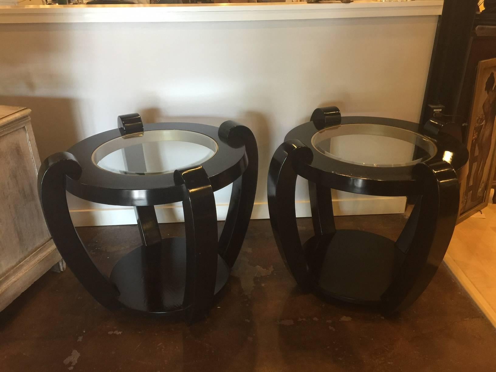 This is a heavy pair of side tables with unique styling, black and gold lacquer, and beveled glass top inserts. There is a shelf at the bottom of each table and they are bracketed by substantial braces creating this MCM styling. Made of heavy wood