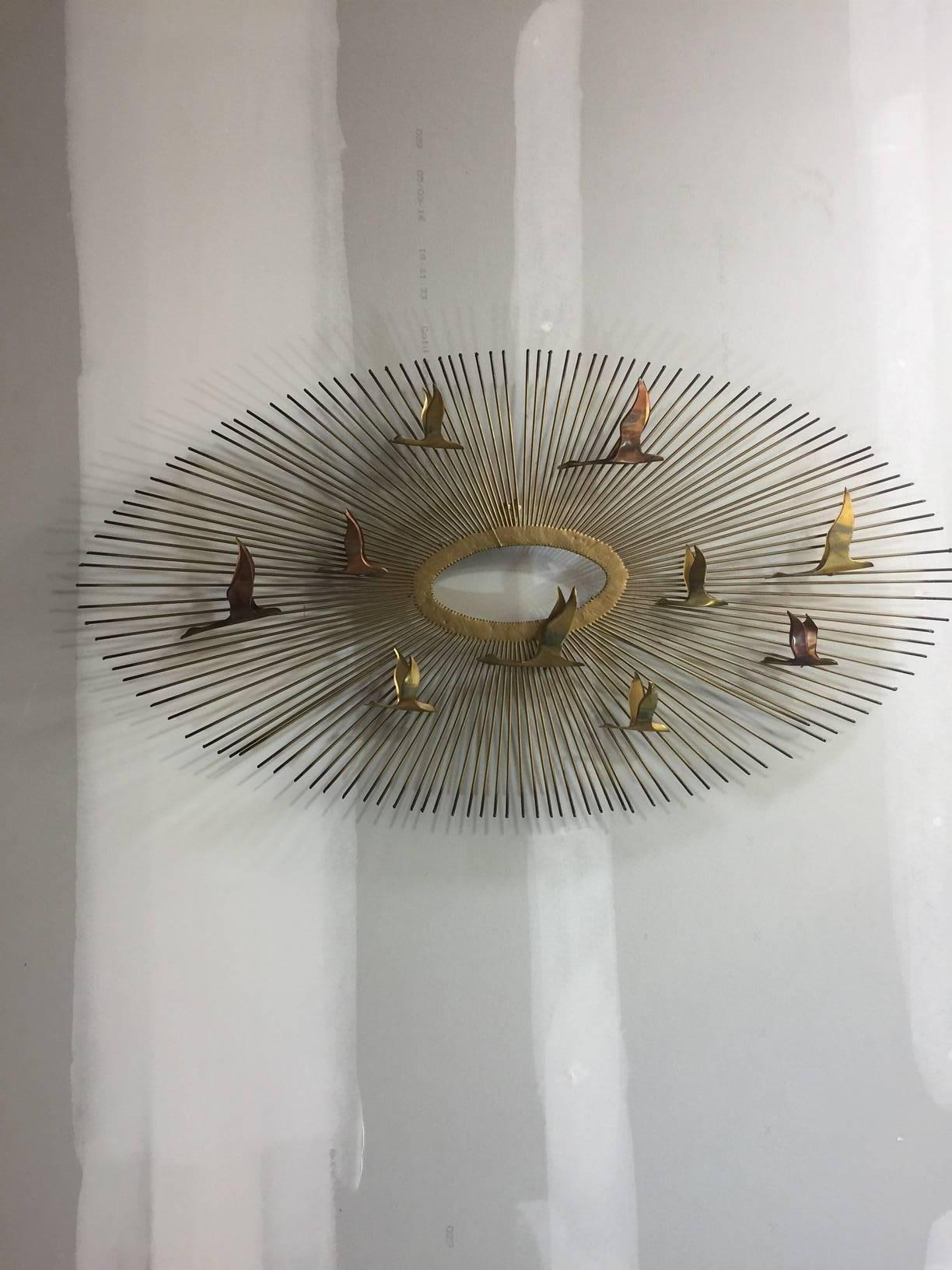 This classic sunburst piece with birds is in the style of Curtis Jere and is frequently attributed to the Jere design team, but it is unsigned and is probably not attributable to Jere.

The brass and copper birds circle the spokes of the sunburst. A