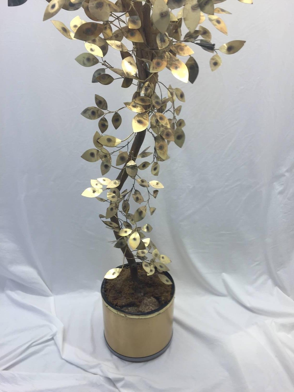 This vintage Jere piece consists of brass patinated leaves and stems emanating from a wooden tree trunk. It is mounted in a brush brass planter with a plastic insert. The leaves show some patina. Great vintage condition.