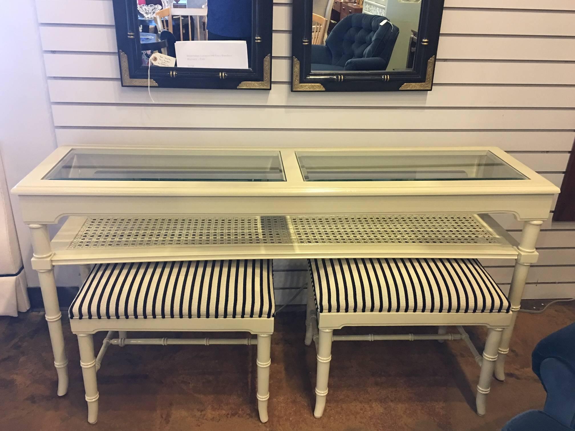 This sweet set has been professionally lacquered in a cream off-white. Two beveled panels on the top of the console, a caned shelf, and two stools or benches that neatly slide under the console or come out for use as seats, side tables, or