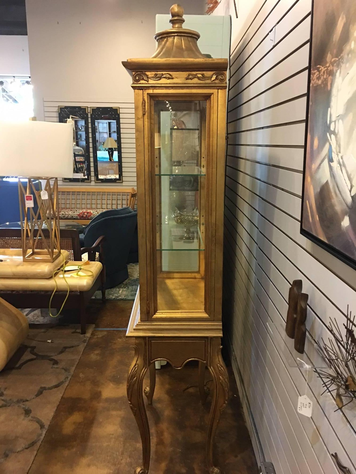 This piece is probably from the 1940s and is in excellent condition. It contains a lighted interior with gold glazing on the mirrored interior and two glass shelves. The pagoda crown is topped with a finial and the Queen Anne legs provide graceful