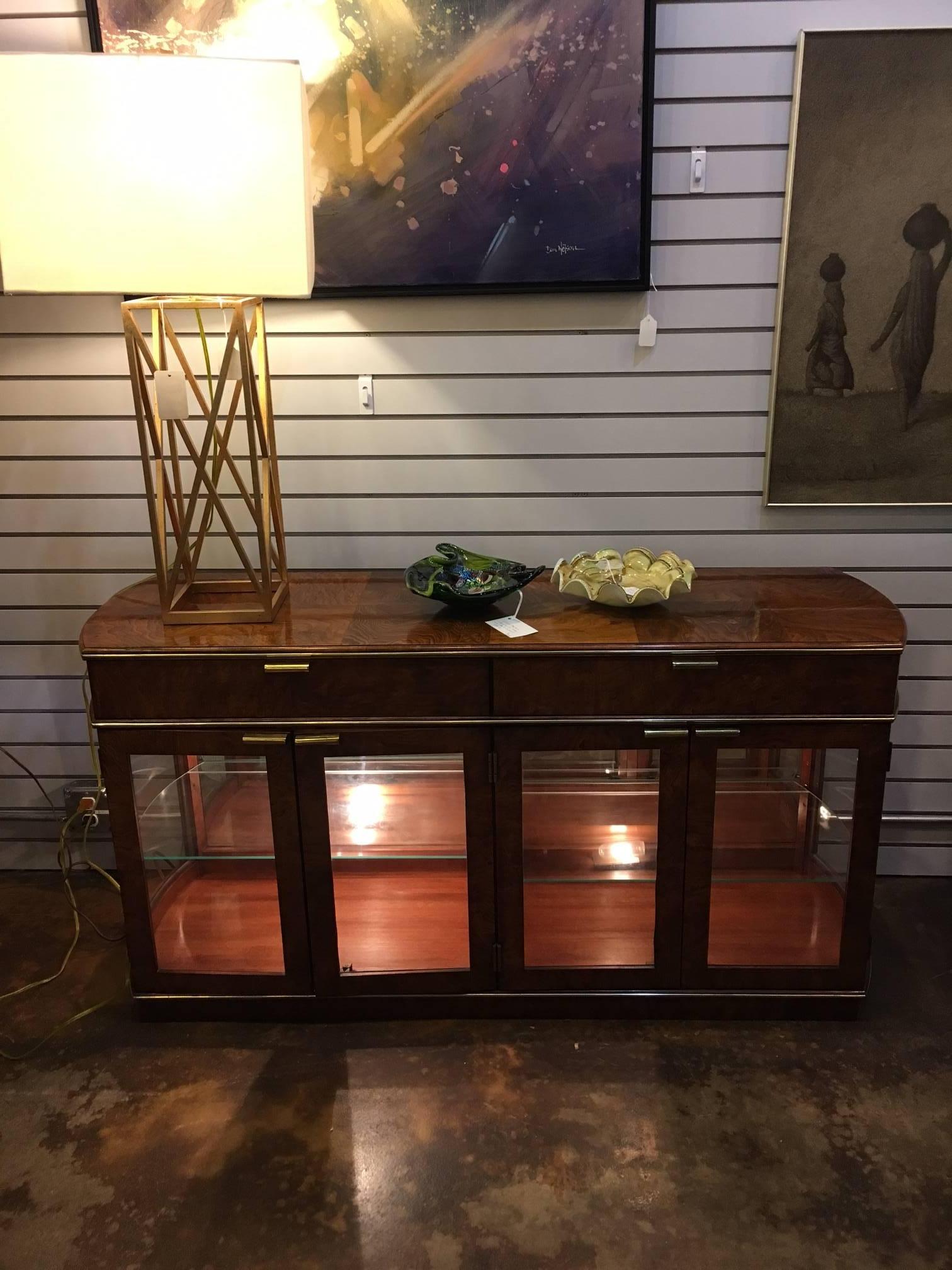 This piece is small sized making it perfect for an apartment or small study or sitting room. It is made of gorgeous burl wood and glass with brass trim. It features a lighted interior with glass shelves, making it idea for showcasing artifacts,