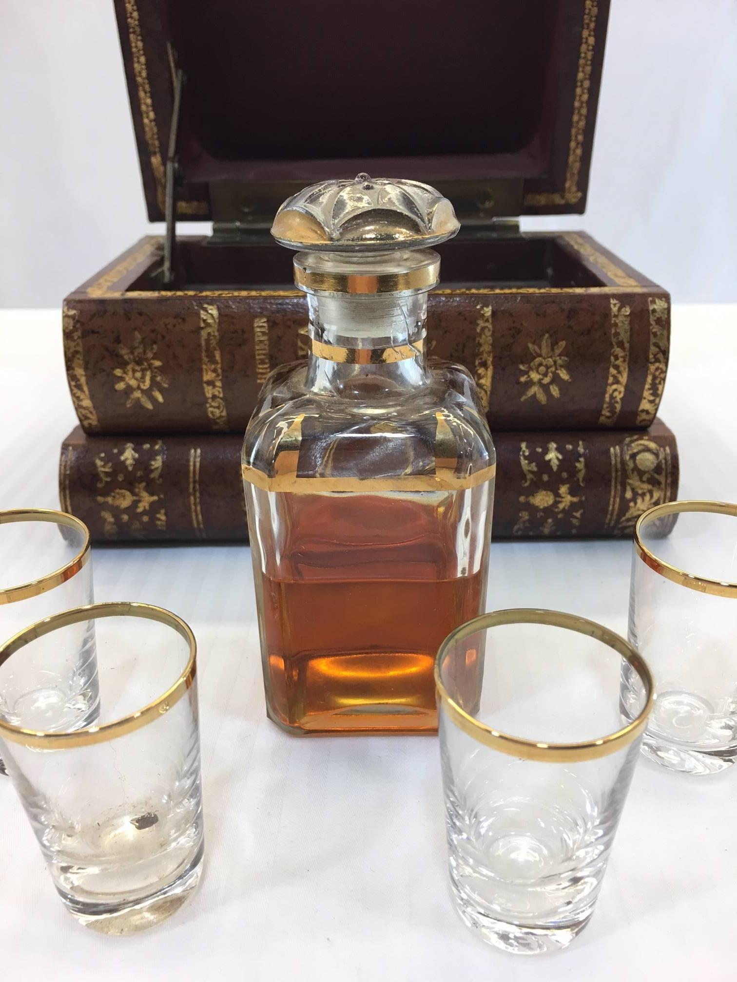 This set holds one decanter and four cordial glasses and even a bit of scotch from some prior life. The glasses and decanter are gold trimmed and fit neatly into the leather box with gilded markings, cleverly disguised as a stack of books. Brass