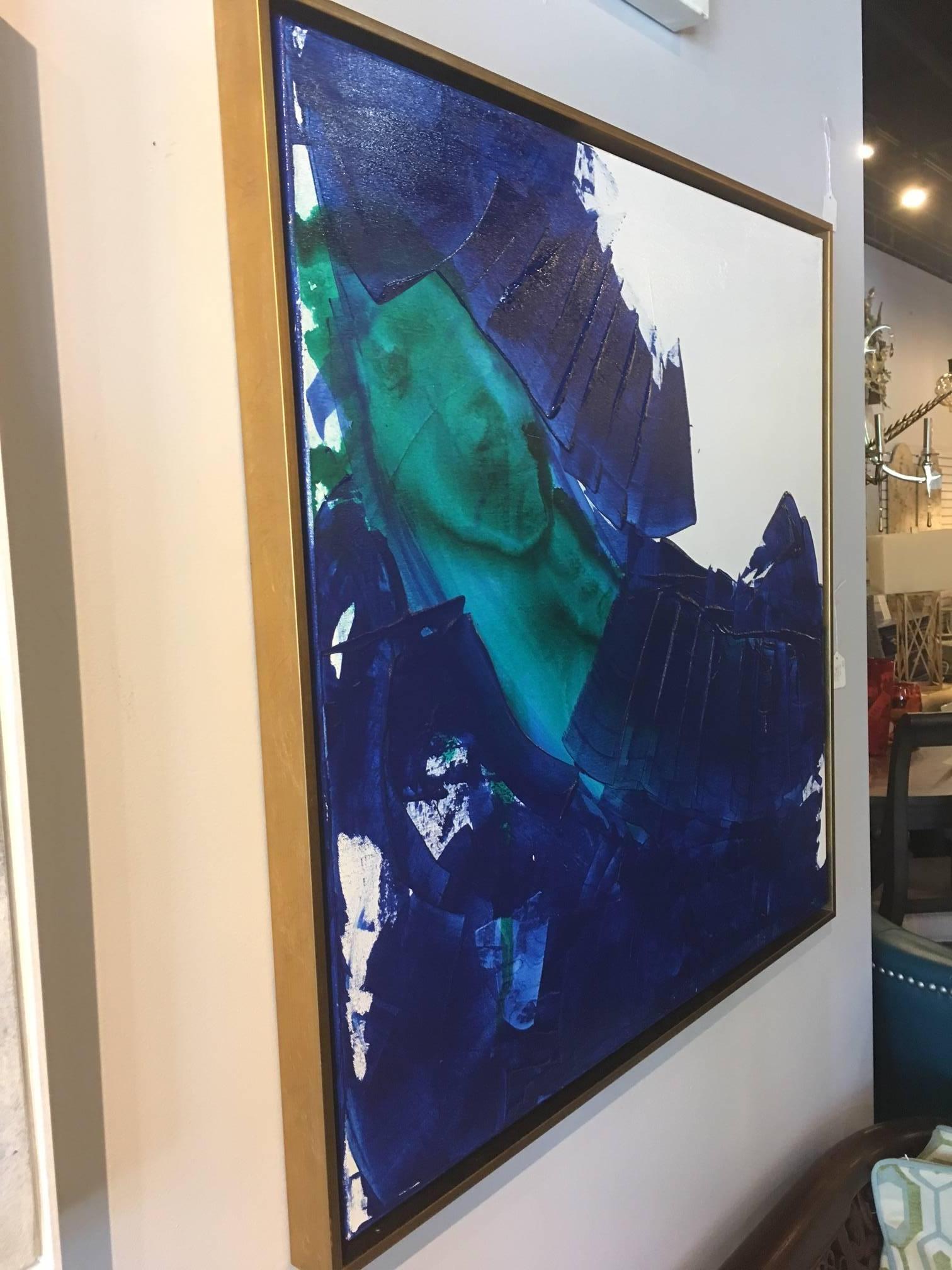 Abstract painting by Raleigh artist Ellan Maynard is layered in rich blue and teal green against a white background on stretched canvas measuring 36 x 36. The painting has been set in a gold float frame with a finished measurement of 37