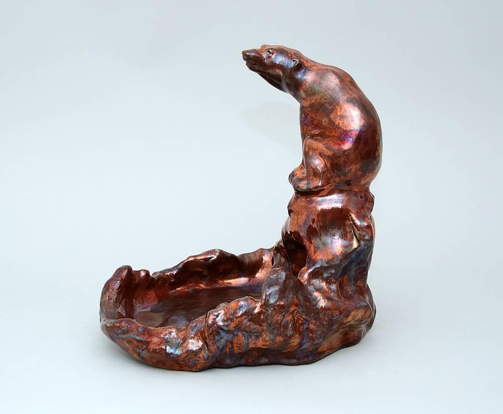 Søren Kongstrand, own studio, Denmark.
Stoneware figure of a polar bear above a pool, metallic red glaze, circa 1915.
Measures: Height 11 1/2" (29cm), width 11 1/2" (29cm).
Incised "SK."
Excellent condition, no chips, cracks