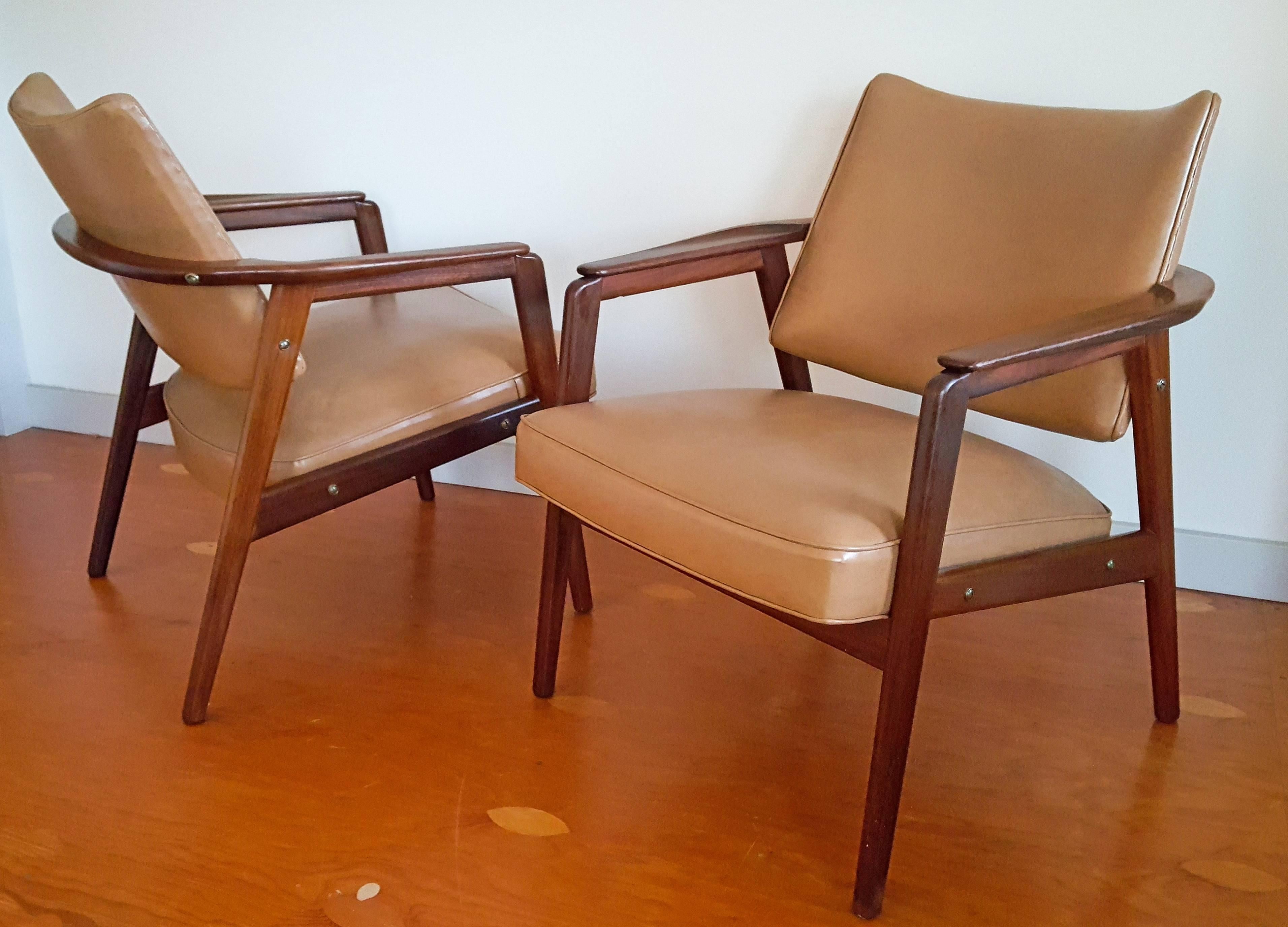 A stunning pair of Mid-Century sculptural teak lounge chairs in the style of Sigvard Bernadotte. These stunning chairs date back to the mid-1950s and are in excellent condition upholstered in original tan vinyl.