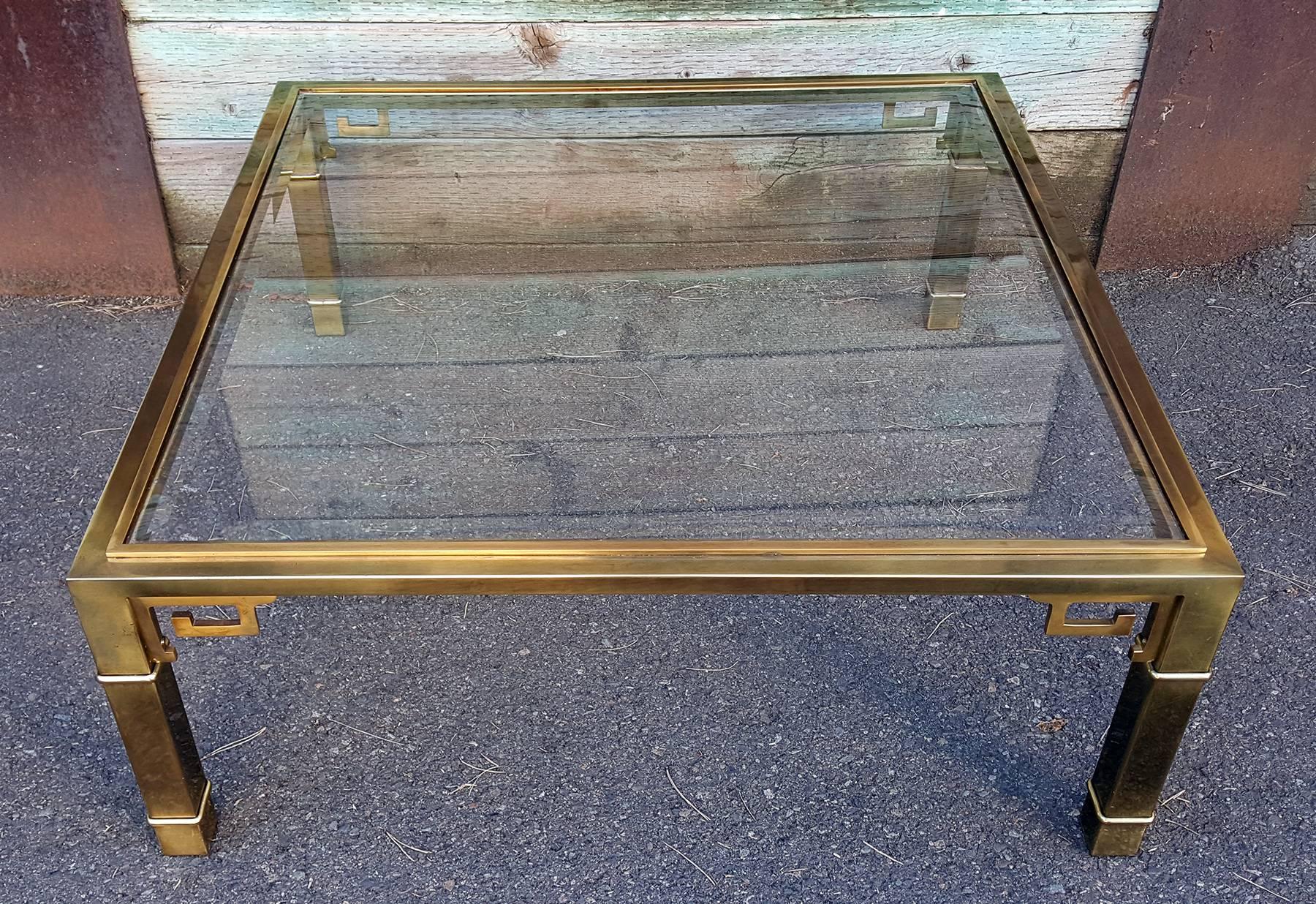 A striking brass coffee table designed by Mastercraft. This brass coffee table embodies the Regency / Hollywood Regency style with a polished contemporary look. The table features a beveled glass top and has a wonderful patina to commensurate with