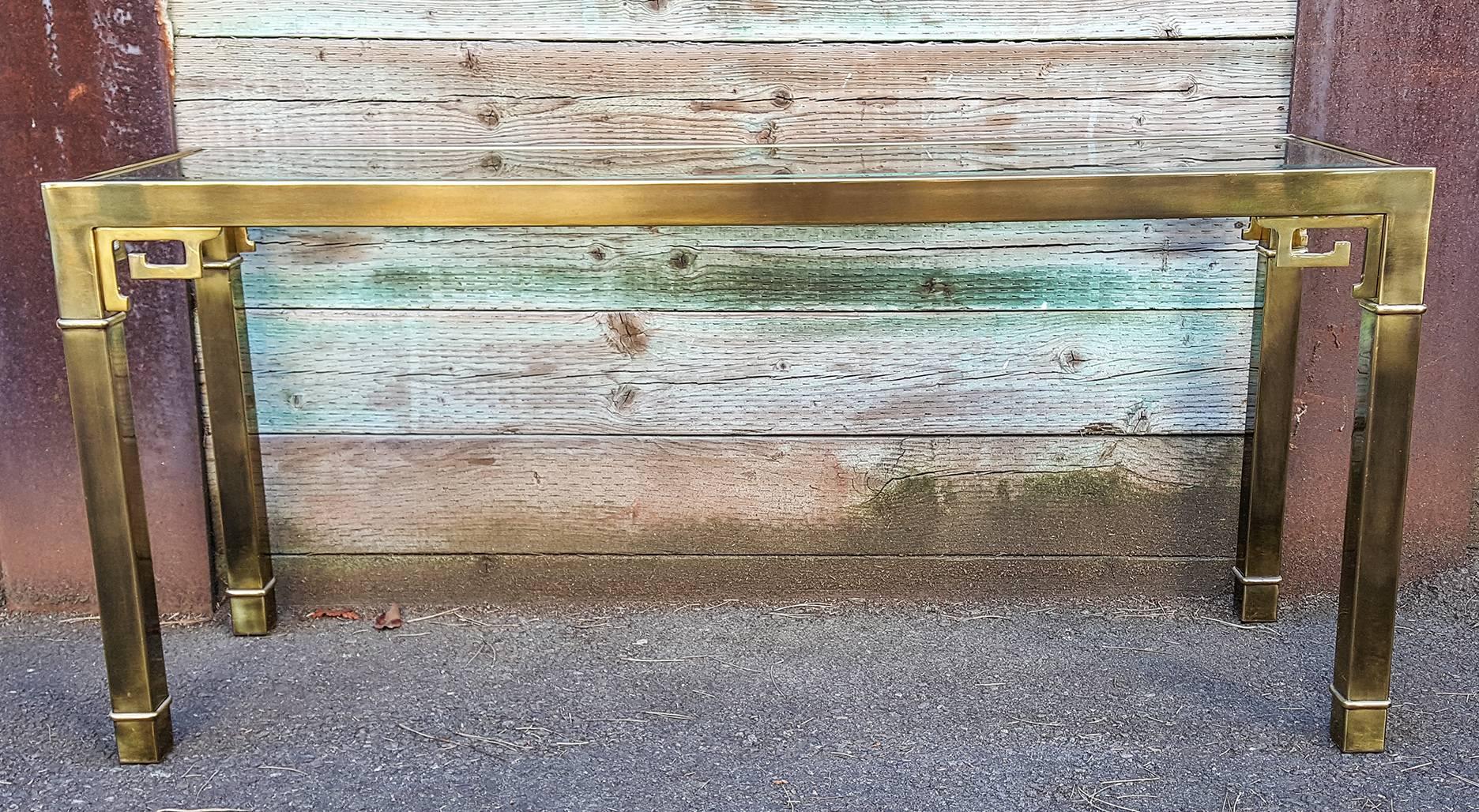 This sofa table or console table is absolutely stunning, circa 1970, this console table features Mastercraft's seamless brass Greek key design with a beveled glass top. Clean lines and contemporary styling make this Hollywood Regency style piece a