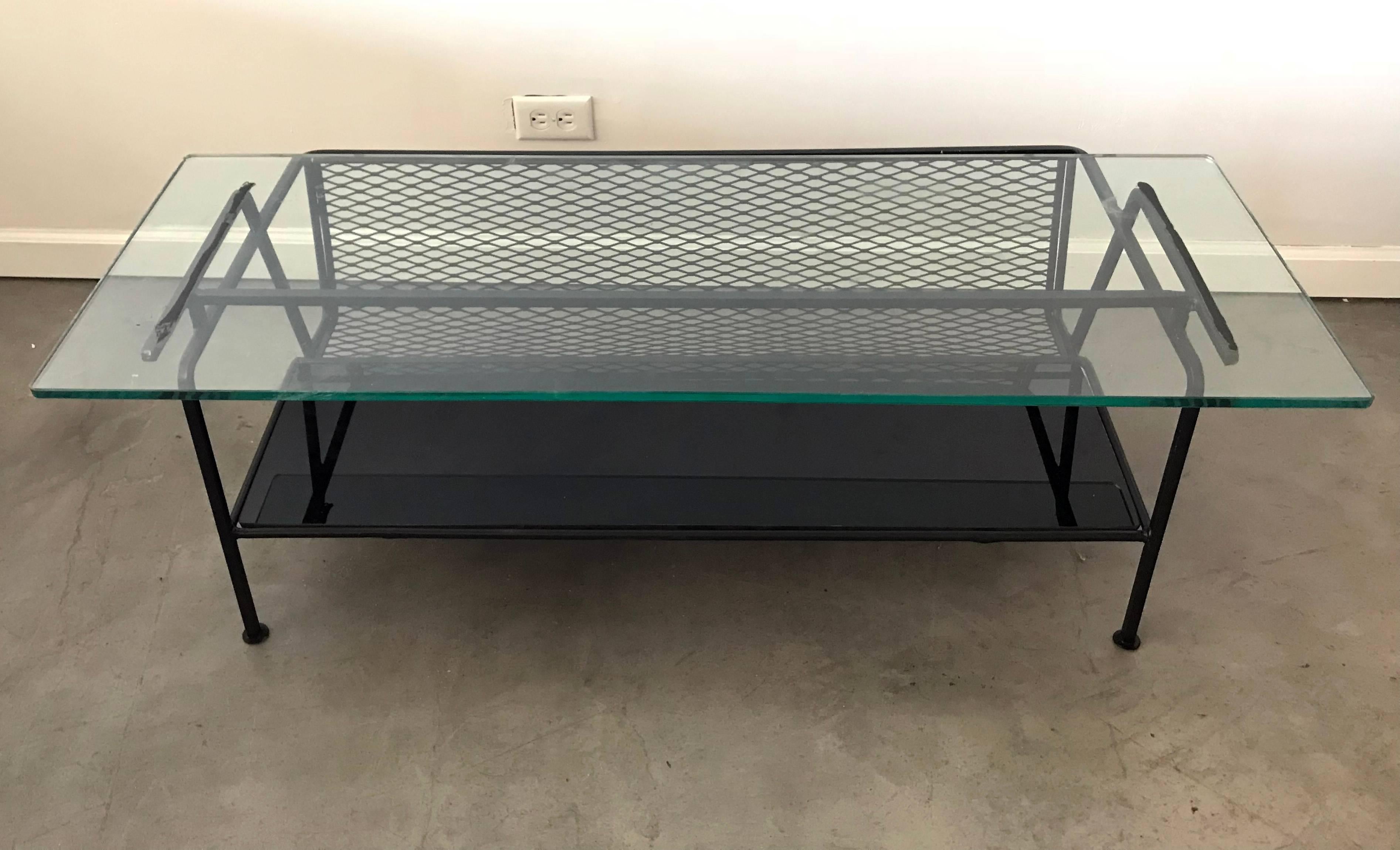 Such a simple clean design; this coffee table designed by Maurizio Tempestini for Salterini is the embodiment of Mid-Century Modernism. The table features a black glass bottom, with a clear glass top and mesh magazine rack. In excellent condition!