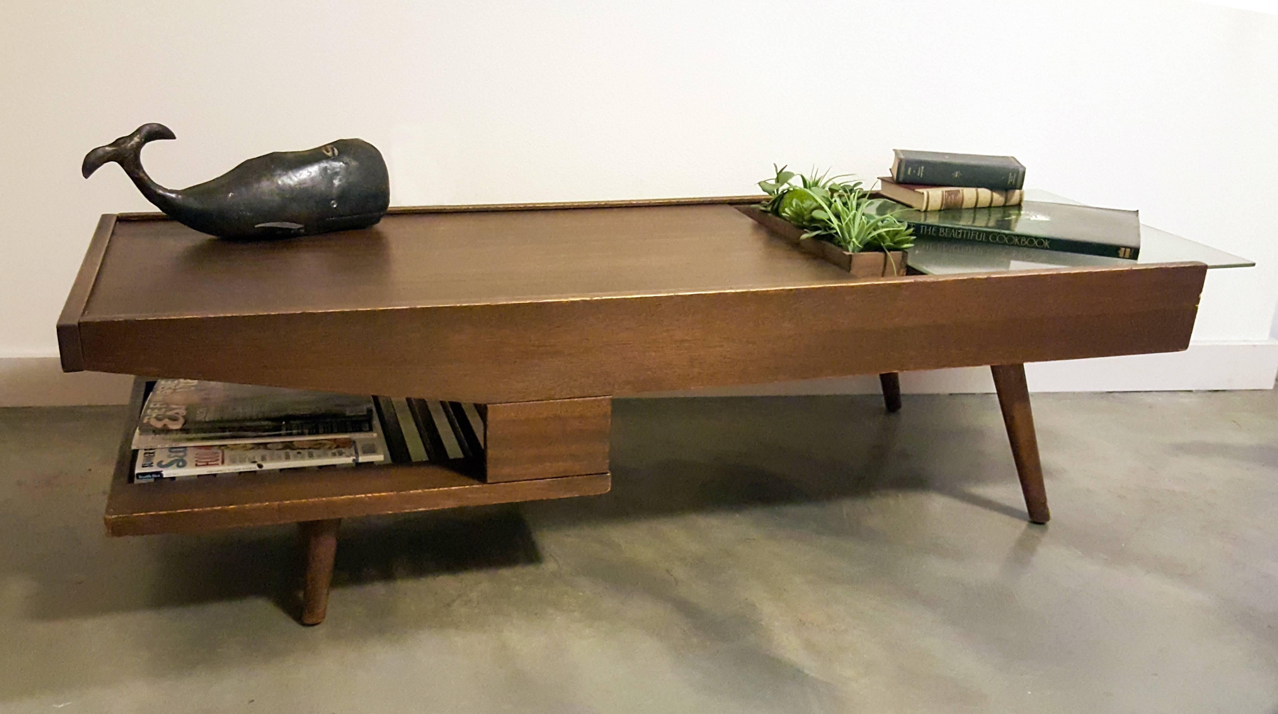 A stunning, rare John Keal for brown and saltman coffee table that features a built in bar as well as a magazine rack. The coffee table has been refinished and stained in a satin walnut.