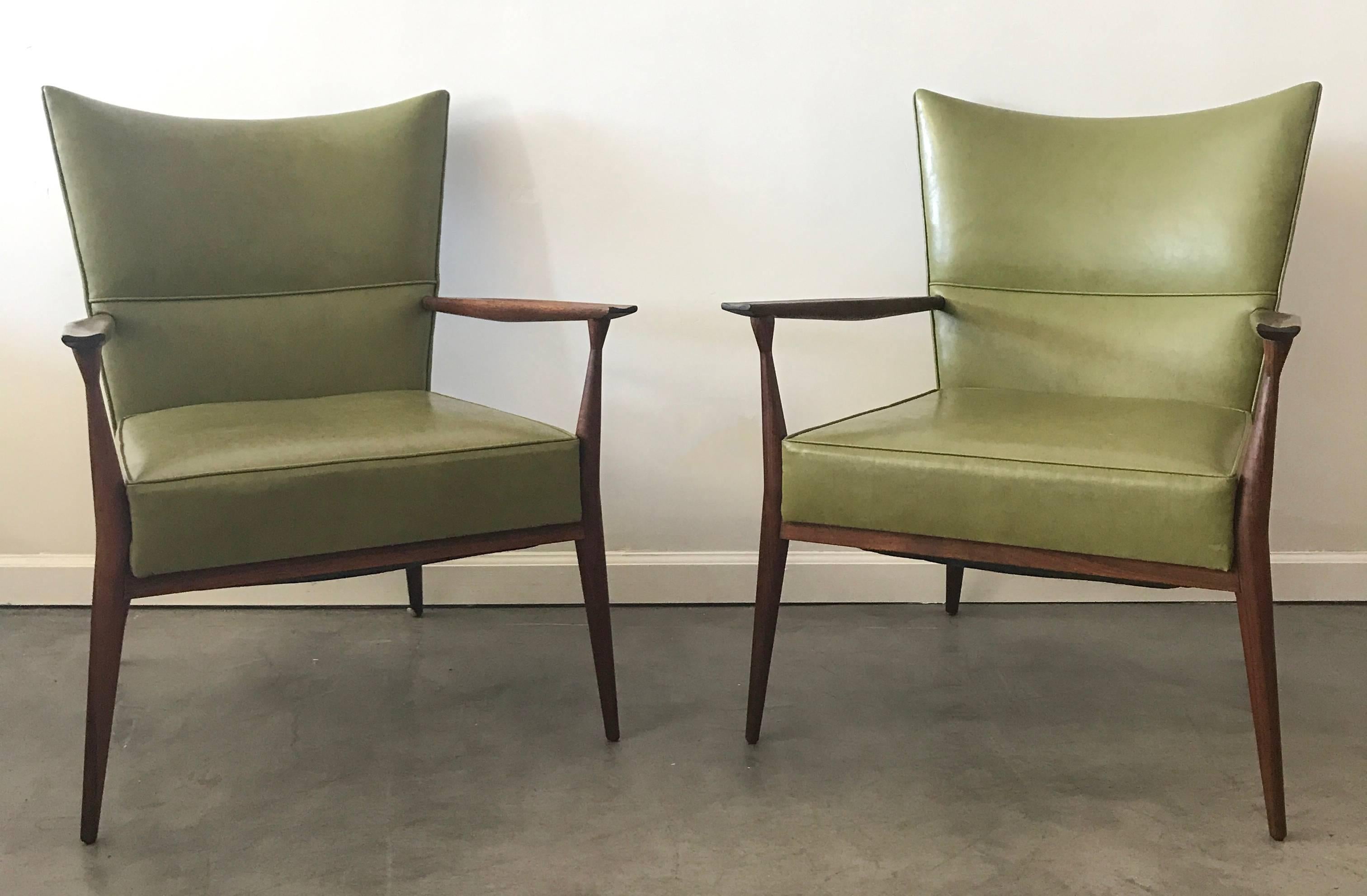 Absolutely stunning and increasingly rare Paul McCobb pull-up armchairs. These chairs are in all-original near mint condition, with very minimal wear to commensurate with age. Sculpted walnut arms and frame with original avocado / olive green vinyl
