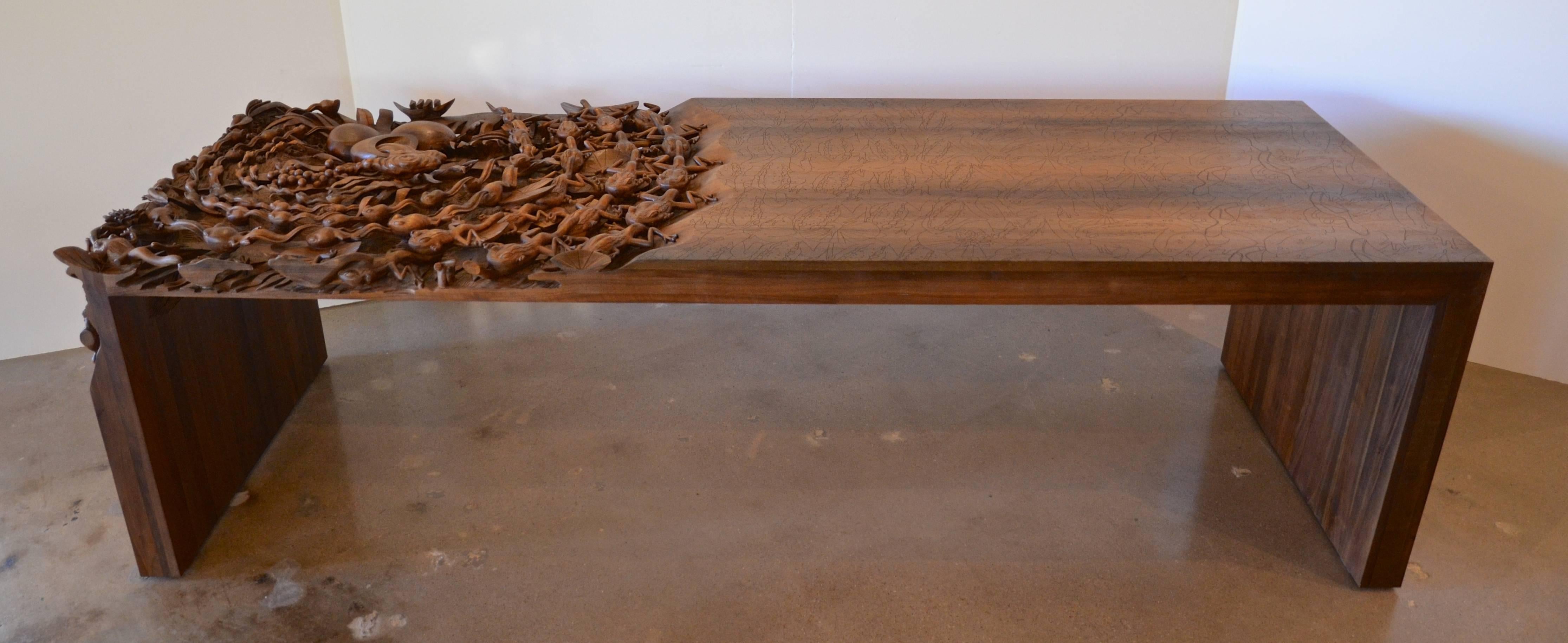 An extraordinary contemporary sculpture and table of American walnut. The table reveals, with intricate layers of hand carving, the story of the Indonesian folk tale of a frog that turns into a prince. Only five tables were created with one now