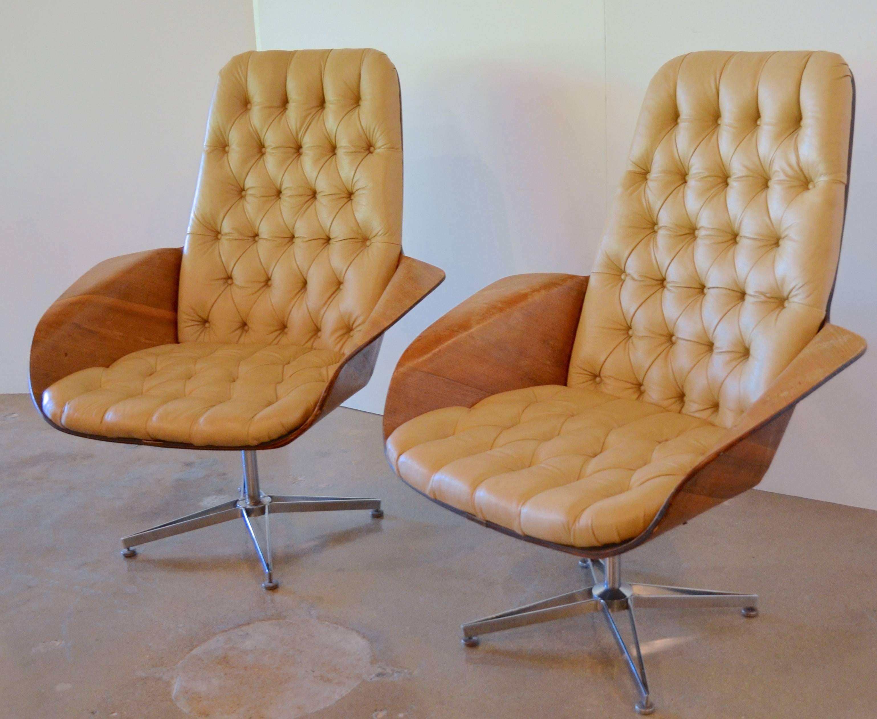 In true Madmen style we have a pair of bentwood swivel chairs by George Mulhauser for Plycraft, USA. With a bentwood walnut shell, the chairs feature tufted tan leather upholstery and a modified chrome swivel base. Label on bottom of chairs