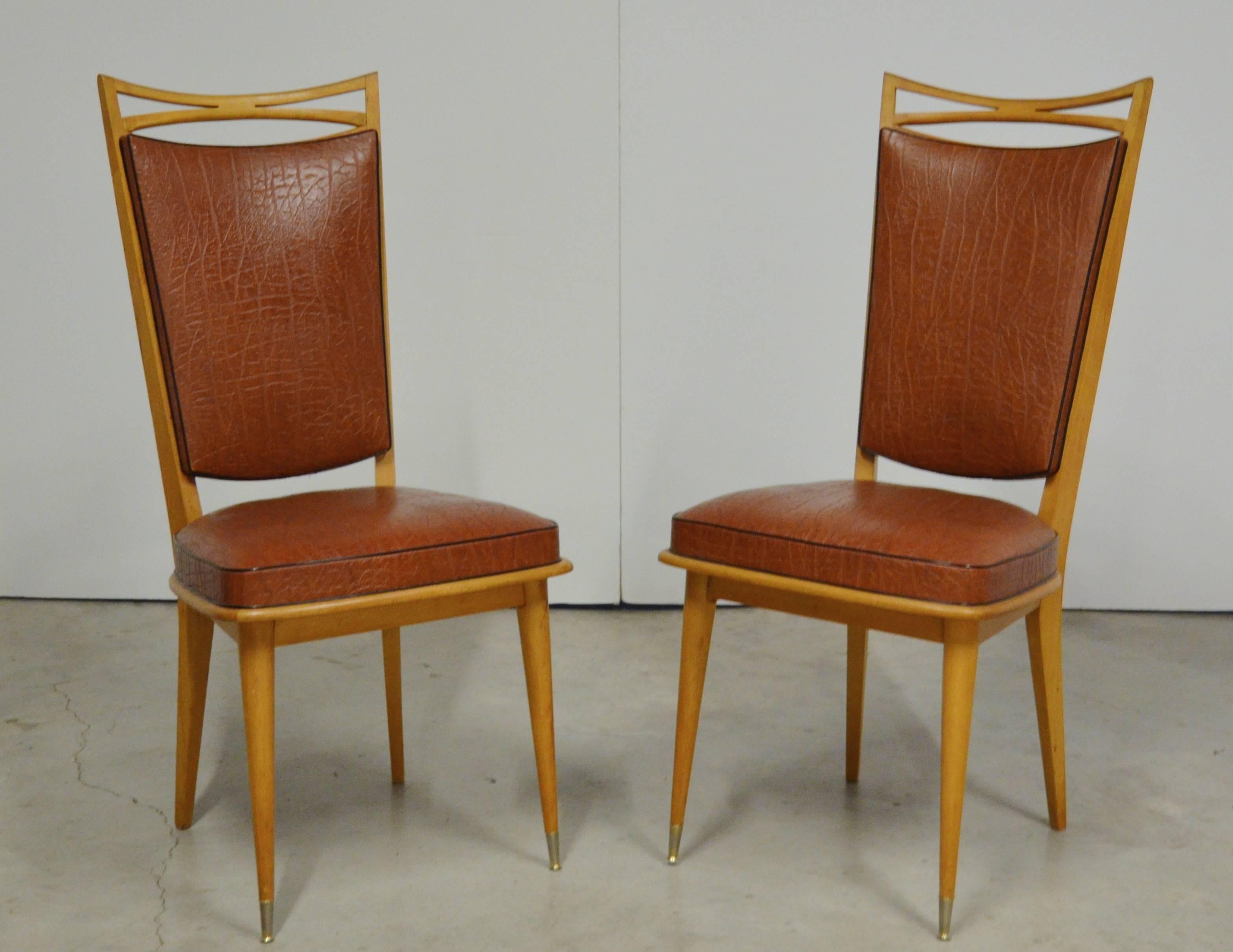 French Art Deco dining side chairs, 1930s, marked Fabrique de Meubles E. Santrossian Draguignan. With a pierced crest rail over upholstery at back and seat on turned tapered legs with brass capped feet. Original vinyl upholstery in good condition.