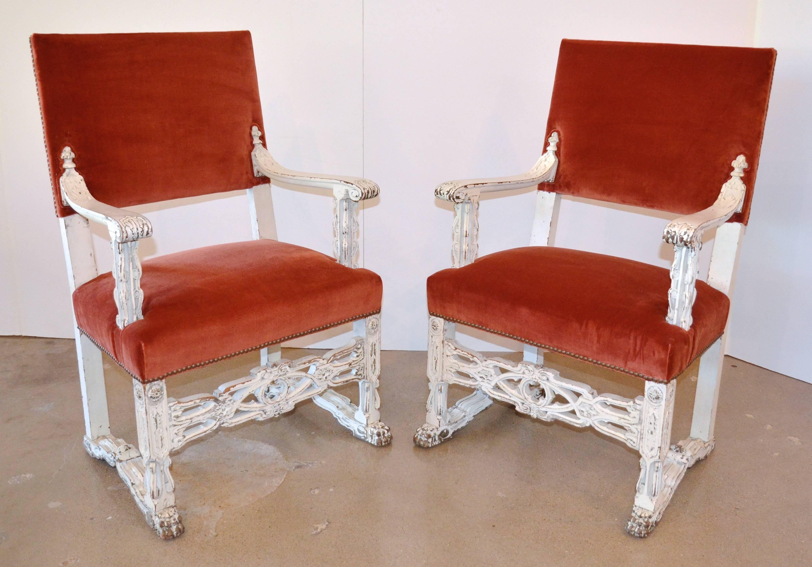 Neo-Gothic or Victorian Gothic styling on painted white, high-backed armchairs. Seat and back are newly upholstered in a rust velvet with brass nailheads, while the patinated white finish blends well with Gustavian settings. This pair make excellent
