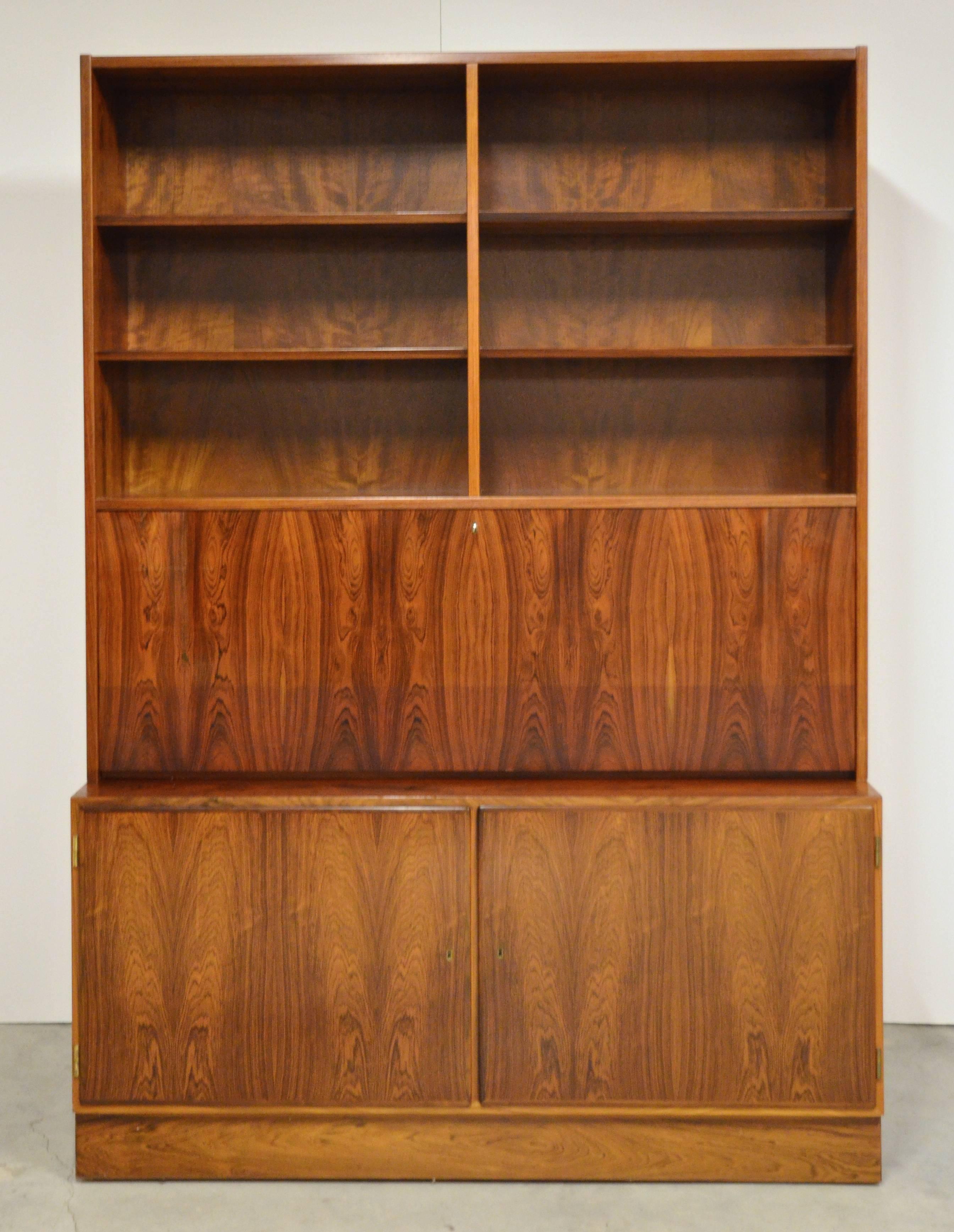 Danish Mid-Century Modern rosewood secretary bookcase by Hundevad, branded on back. This piece has open shelves above a fall front. It has a fitted interior with pull-out tray drawers and shelves on a cabinet base. Piece breaks down into two pieces