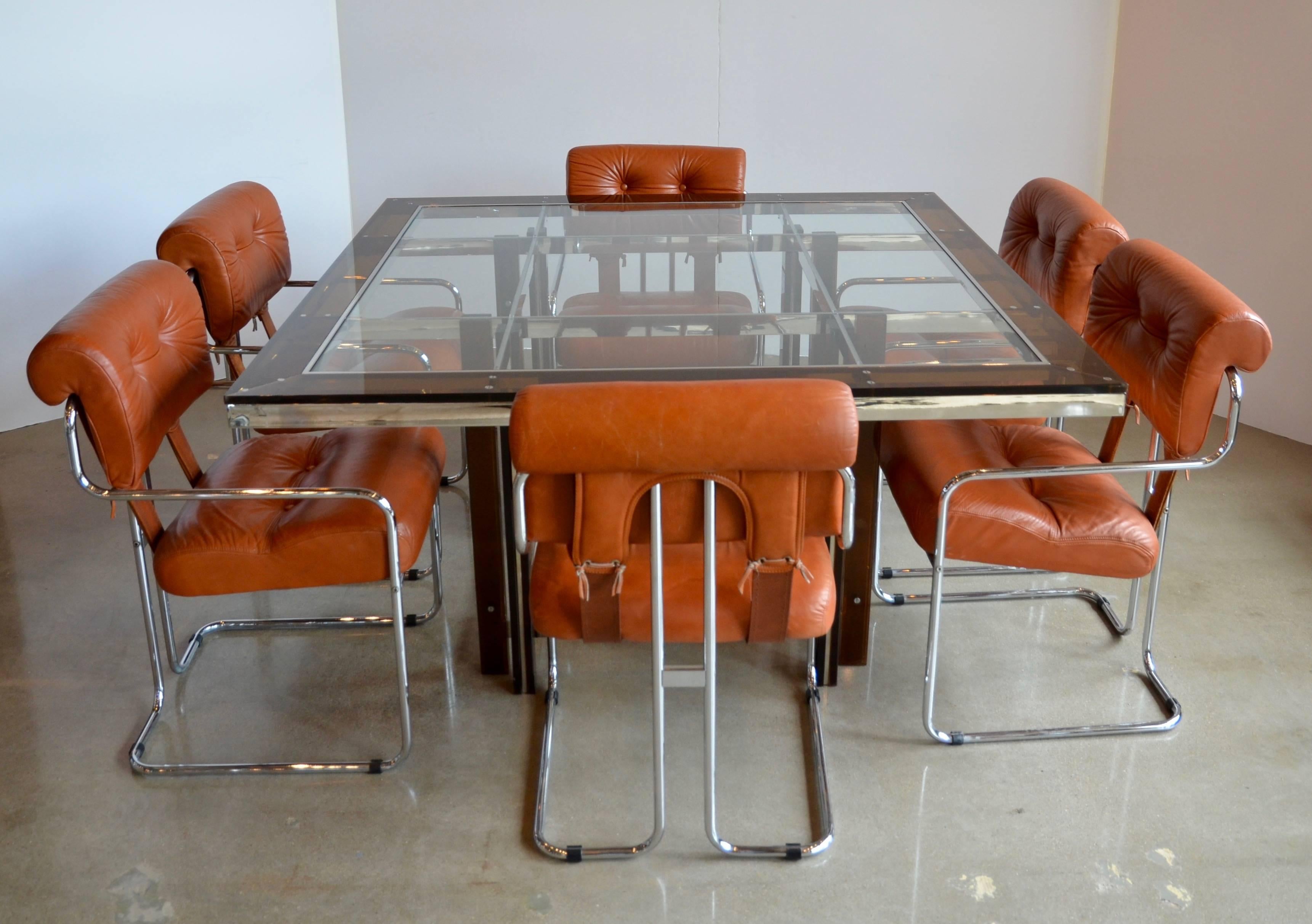 A set of six Tucroma dining chairs designed by Guido Faleschini in 1972 and produced in Italy by Mariani for Leon Rosen's Pace Collection. Simple tubular chrome frame holds comfortable leather upholstered (rust to burnt orange) seats. Leather lacing