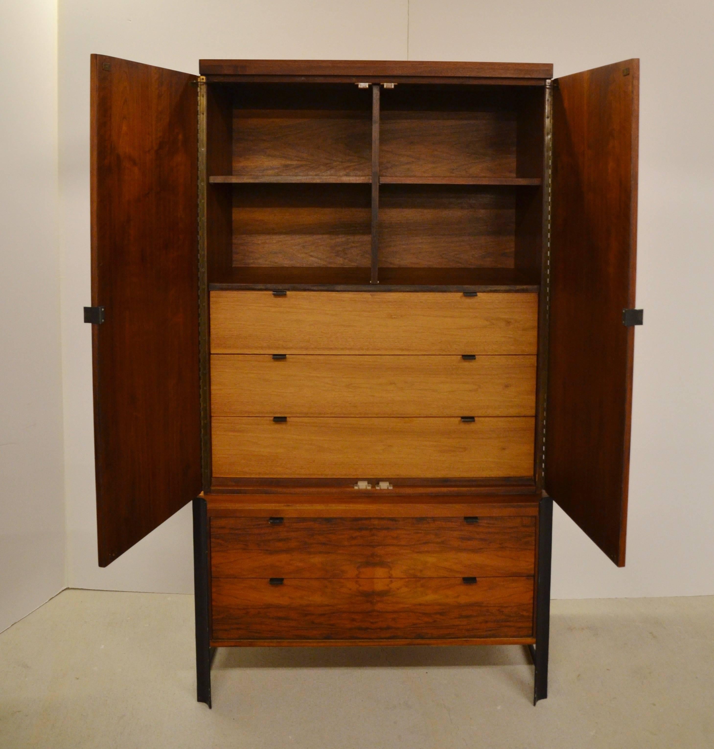 Handsome Mid-Century cabinet by Romweber with flamed wood and unique black steel hardware. Two drawers at base and three additional drawers behind double doors at top. Upper storage compartment has shelves or removable panel allowing placement of TV