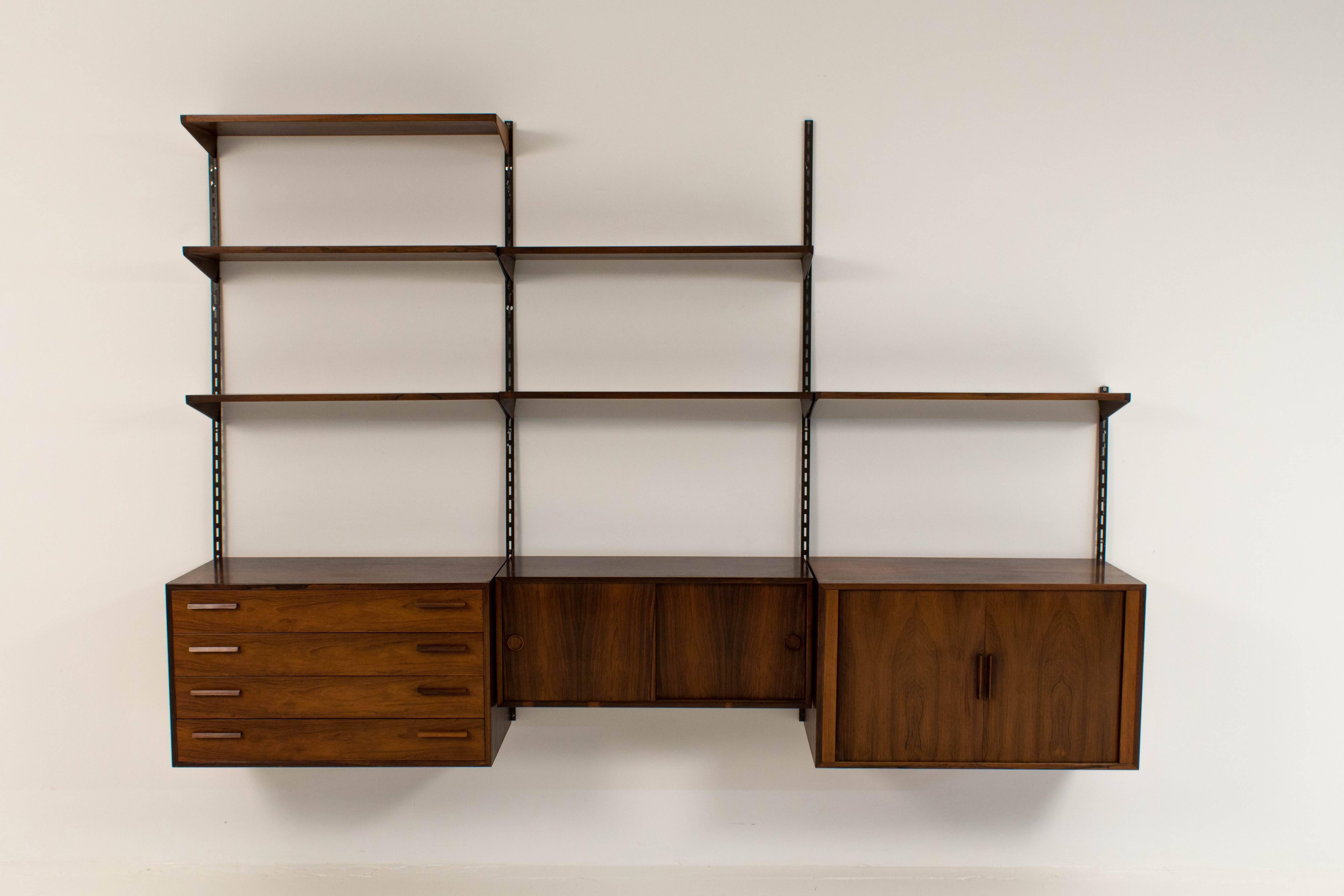 Stylish rosewood wall-mounted shelving unit by Kai Kristiansen for FM Møbler.
Six original rosewood shelves.
Original cabinet with four drawers.
Original cabinet with two sliding doors.
Original cabinet with two blind doors.

In good condition