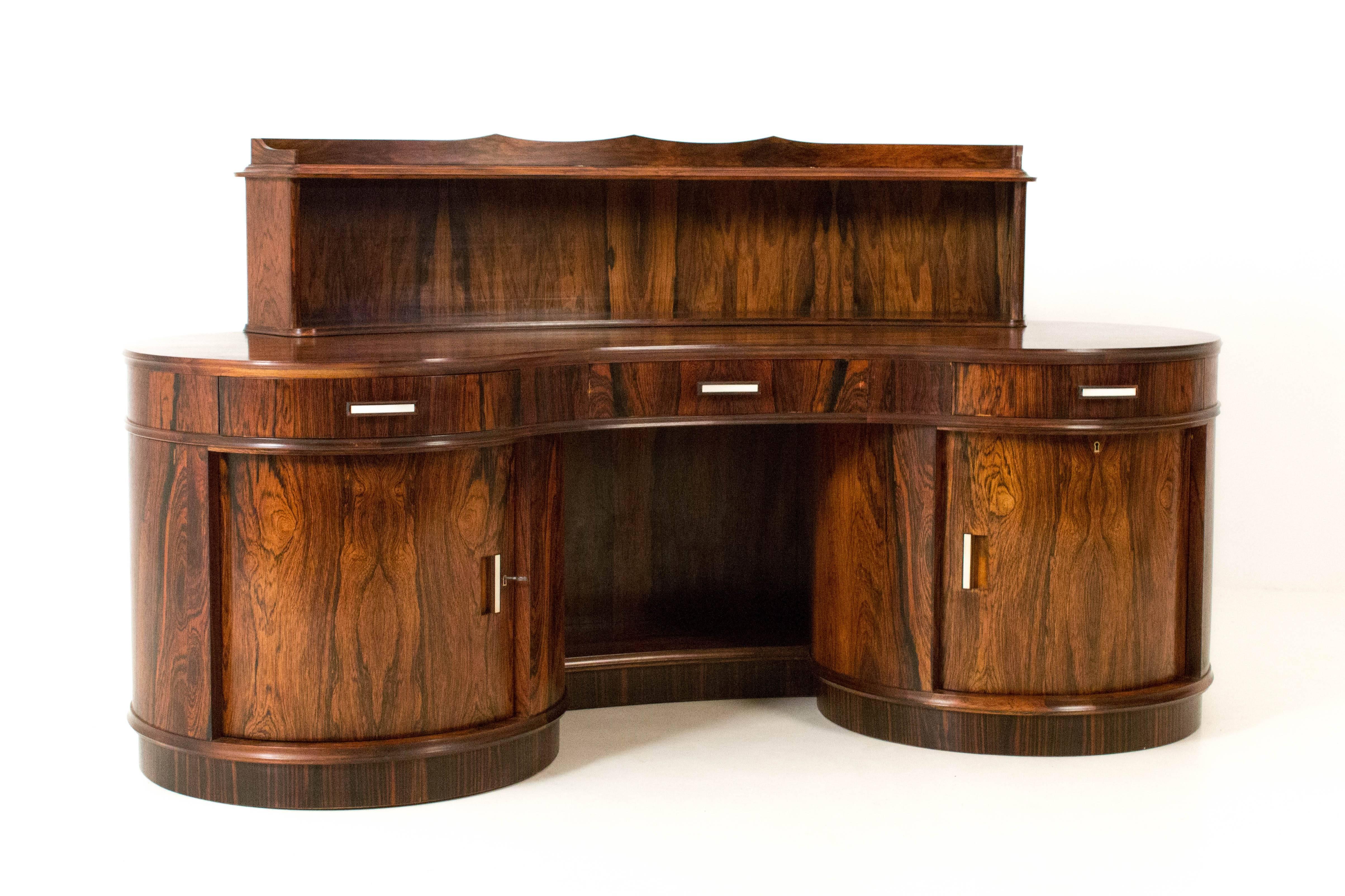Magnificent Art Deco kidney shaped desk with armchair by Reens Amsterdam.
Rosewood and Macassar ebony.
Behind the left door there are nine original solid oak drawers.
The right door is executed with ball-bearing, enabling the drum to rotate