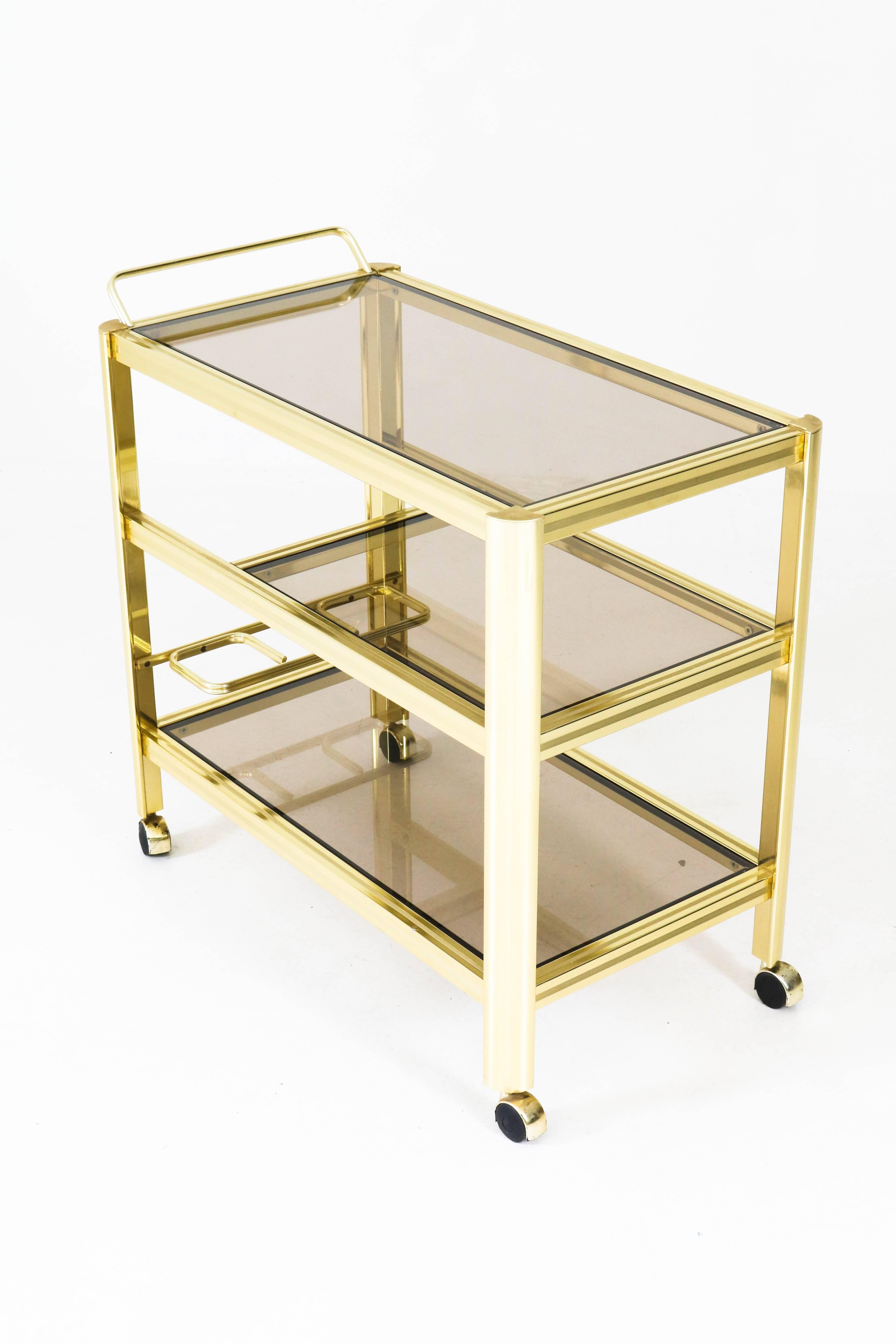 Stunning Mid-Century Modern cocktail trolley, 1970s.
Gilded metal with three original smoke glass tops.
Elegant design from the 1970s.
See picture 5 for the only damage on the trolley.
In good original condition with minor wear consistent with