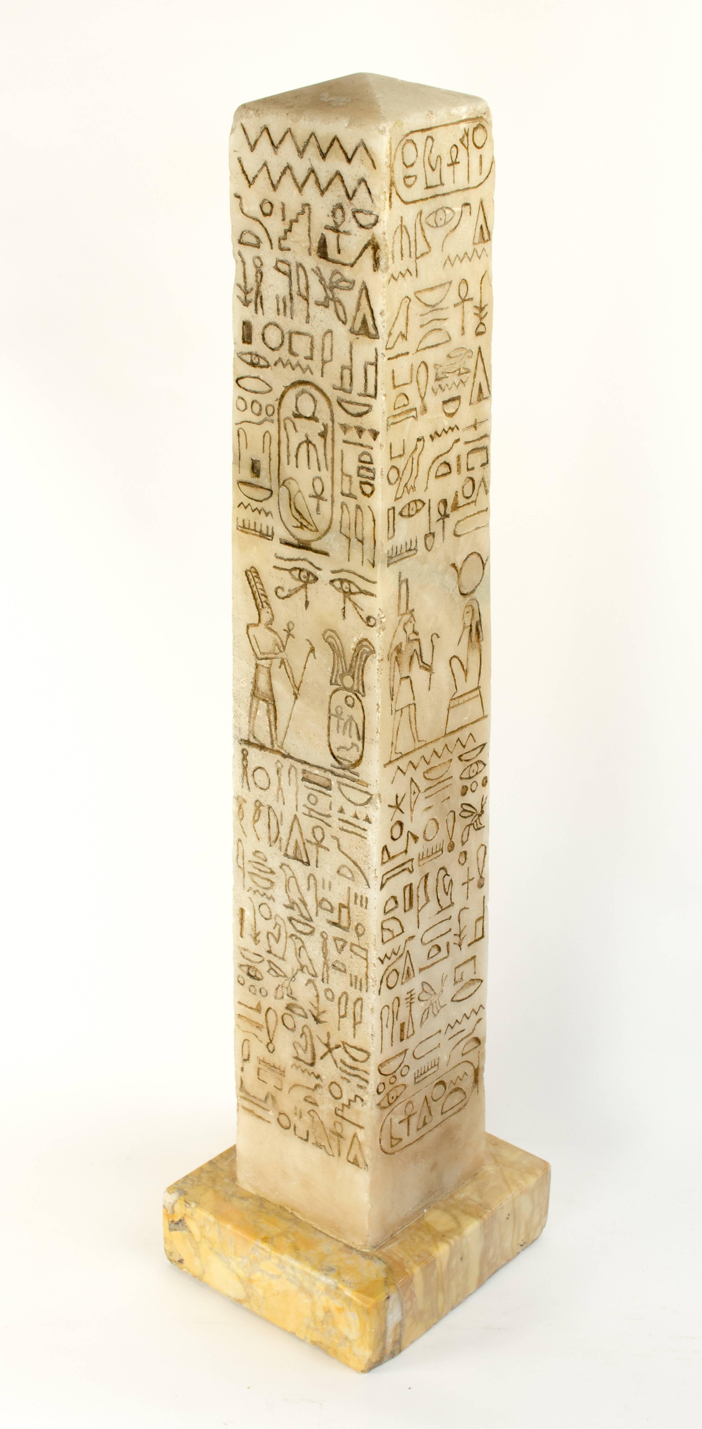 This charming alabaster model set on a yellow marble base is carved on four sides with a lively group of hieroglyphics. It’s unusual shape provides a large surface for a striking group of hieroglyphic interpretations. 

The model doesn’t represent