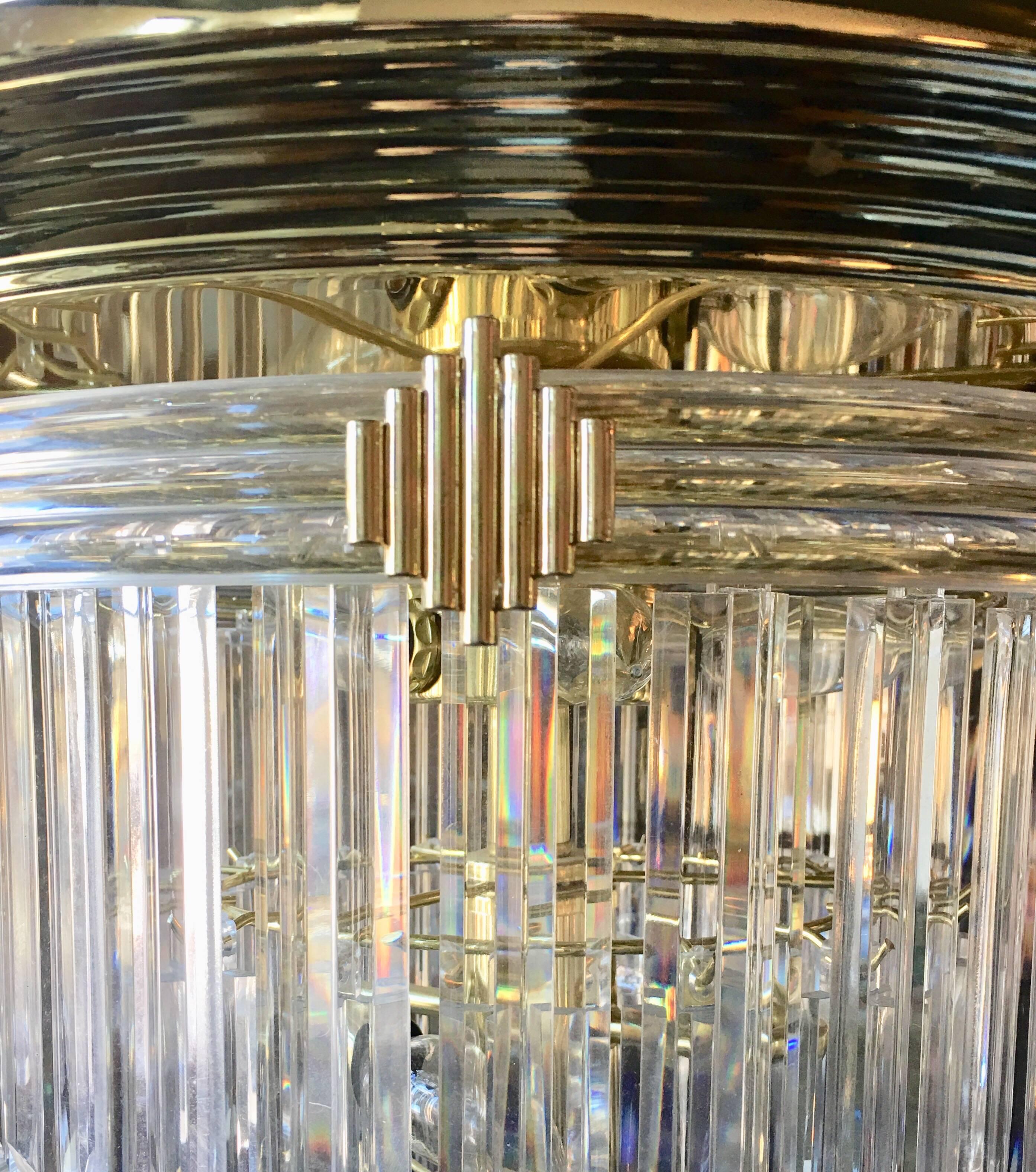 Large modern eight-light four-tier chandelier featuring 60 Lucite prisms suspended from a round brass-plated frame. In the style of Charles Hollis Jones. 

Bottom tier prisms are a different design from prisms displayed on other three tiers.