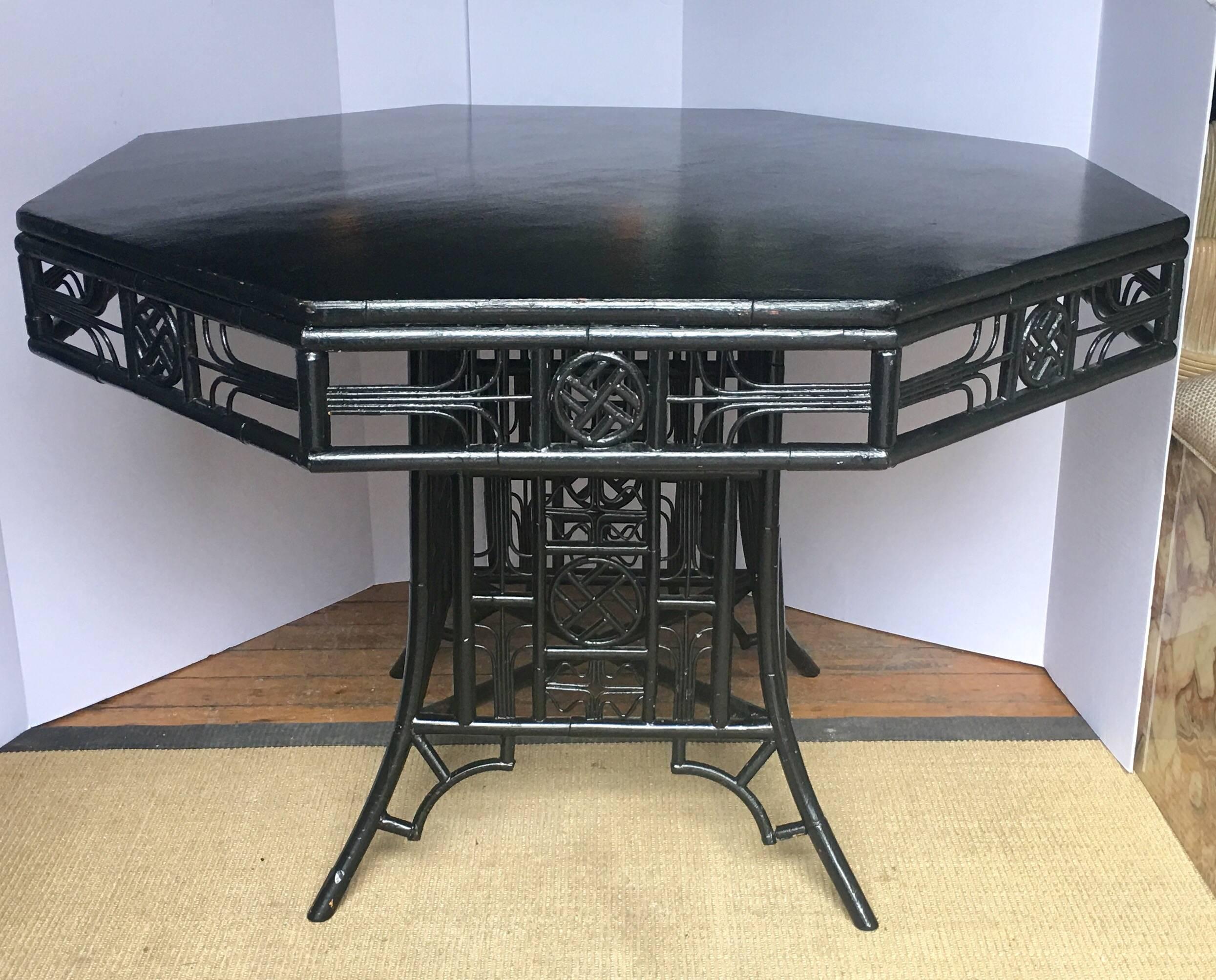 Chinoiserie style Asian motif octagon shaped dining table. Detailed fretwork bamboo wood frame features black gloss lacquer painted finish.  This sculptural piece could also be used as a center table or game table. 
Matching set of four dining