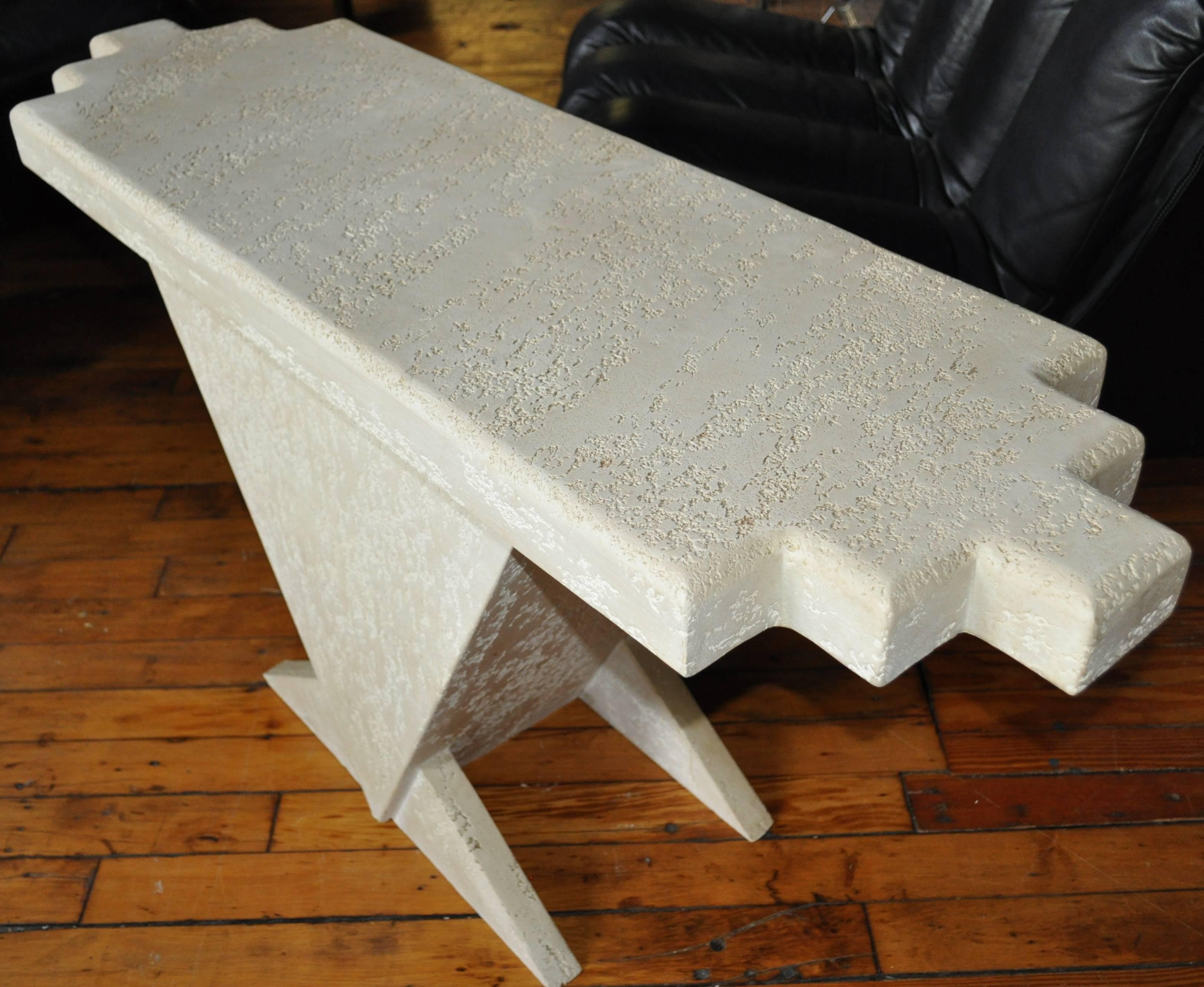 Sculptural entry console table with a triangular form base and a textural cream tone plaster finish.  