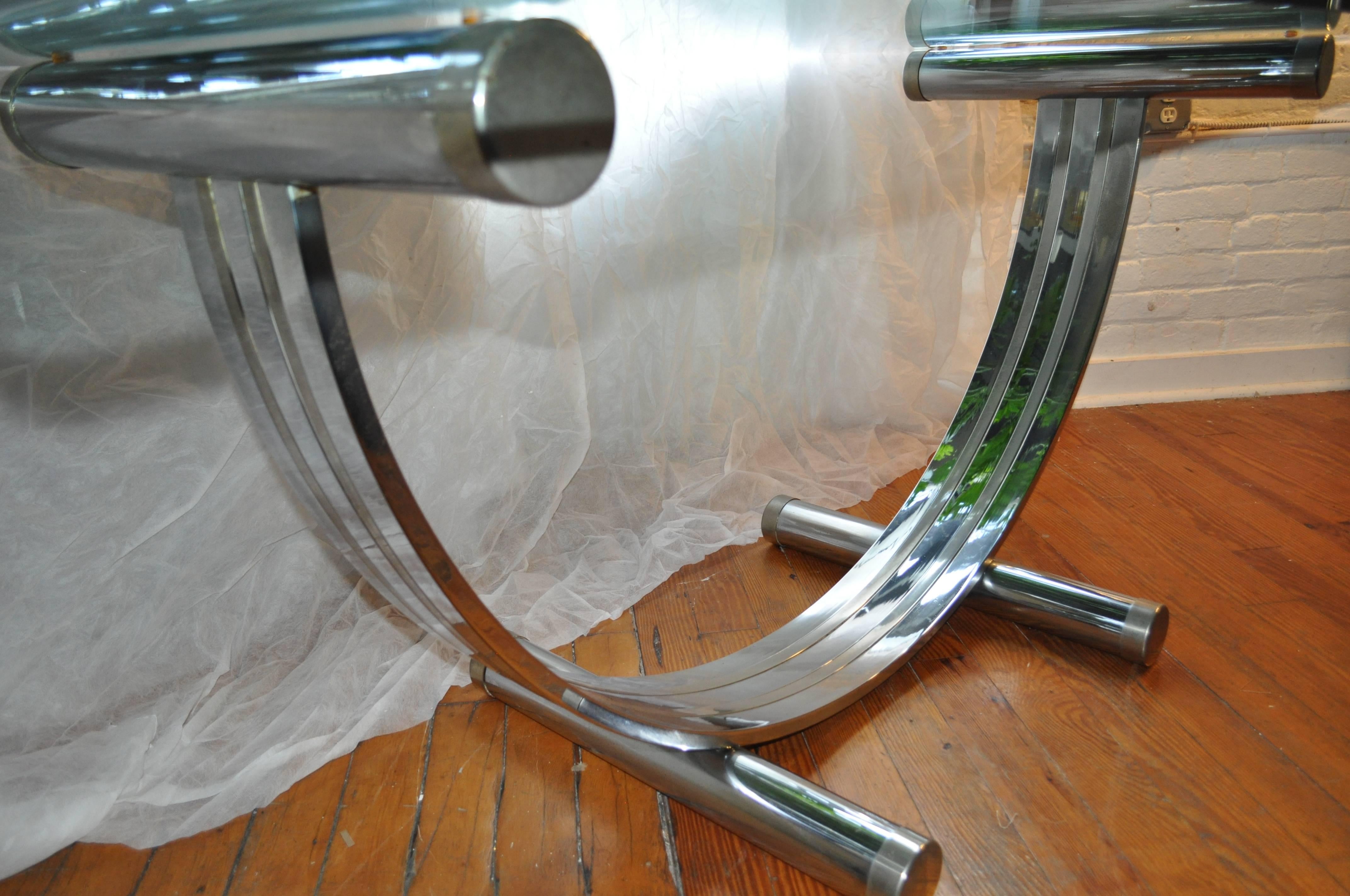 Sculptural Art Deco style dining table attributed to Romeo Rega. Curved arch tubular base features brass and chrome striped design with .5 inch thick glass top. A stunning oversized desk or console table option.