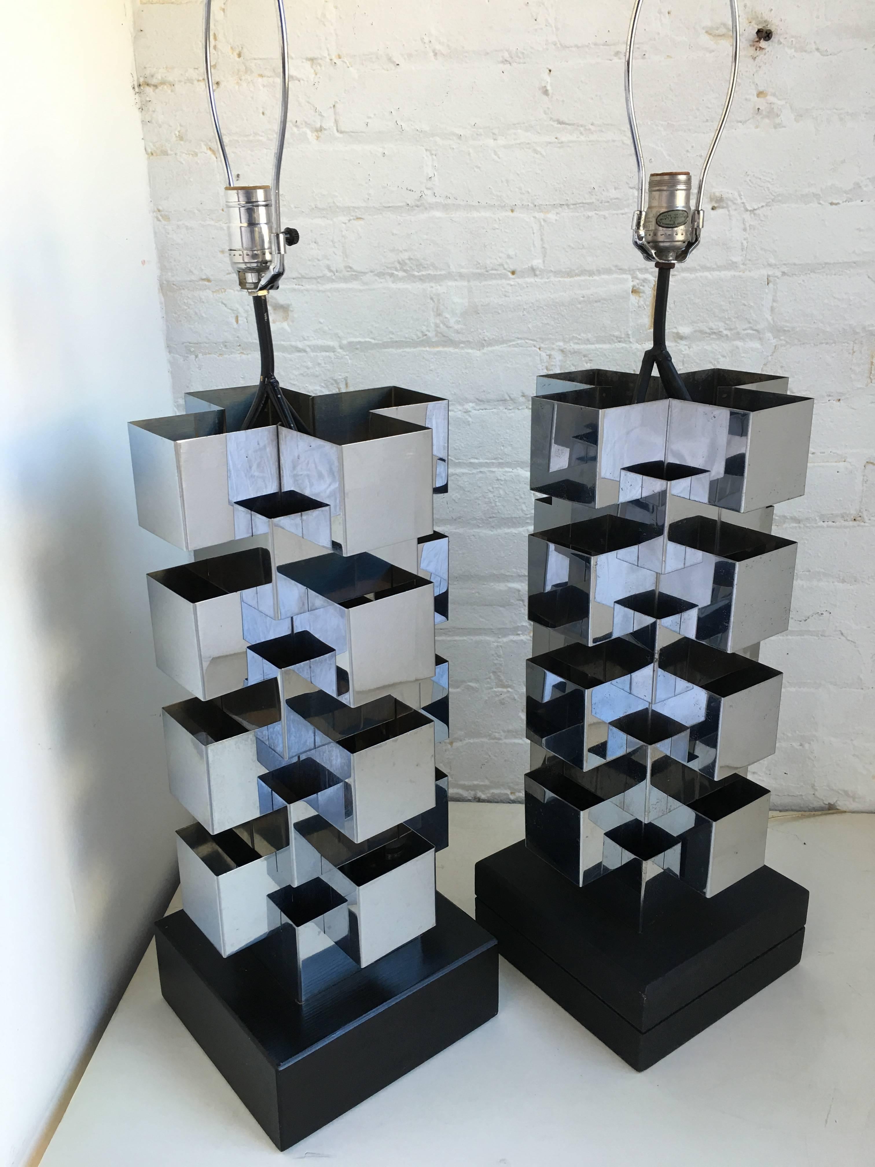 Monumental Mid-Century Modern pair of sculptural cubist table lamps by C. Jere. Each Brutalist style lamp is composed of a series of stacked chrome steel cubes. A switch on the cord illuminates a bulb within the base and top socket. Both wood lamp