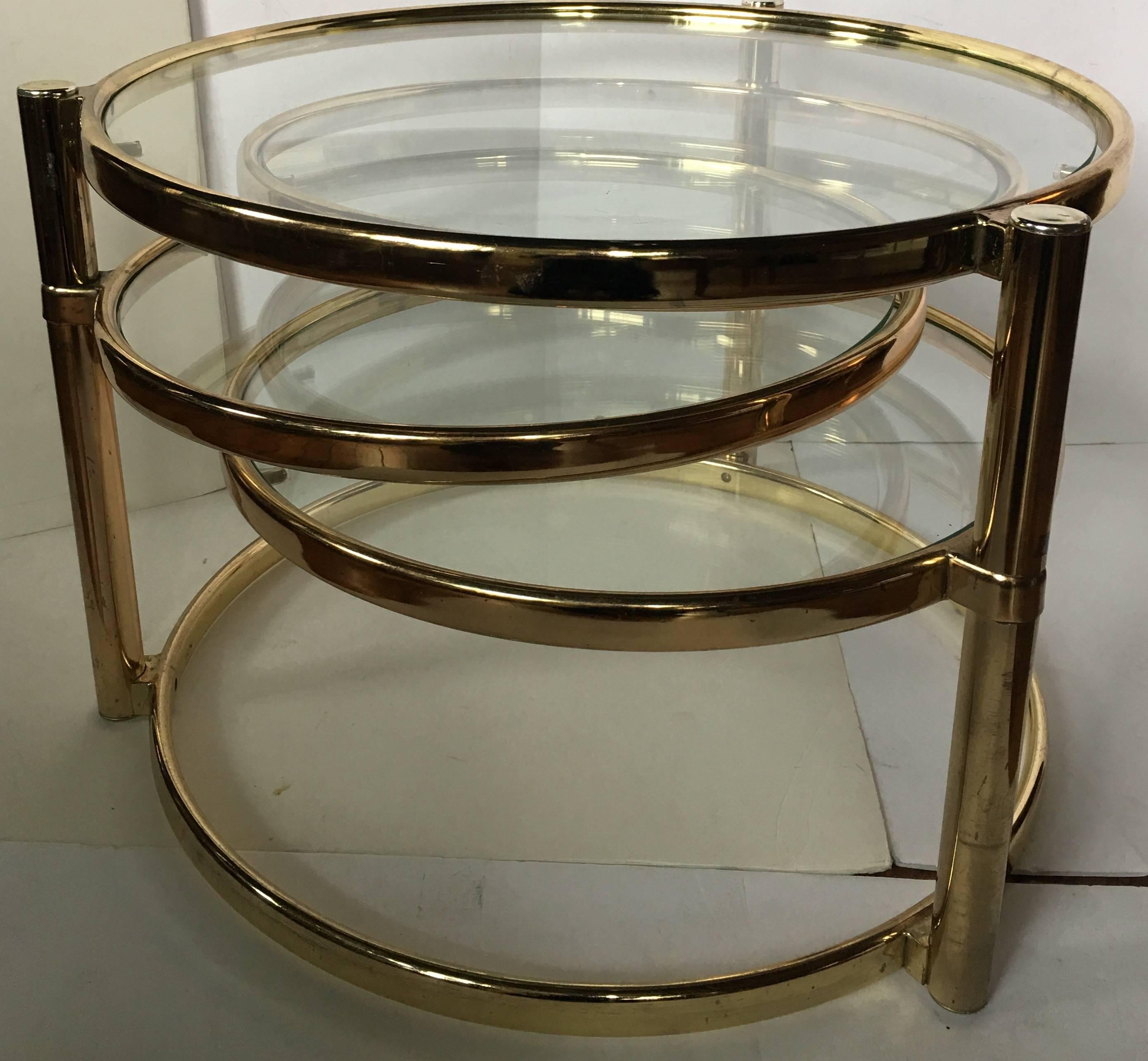 Mid-Century Modern four tier swivel coffee table in the style of Milo Baughman. Table features a brass tubular frame with removable clear glass inserts. Three side tiers pivot and be positioned in many configurations. Table measures 60 inches wide