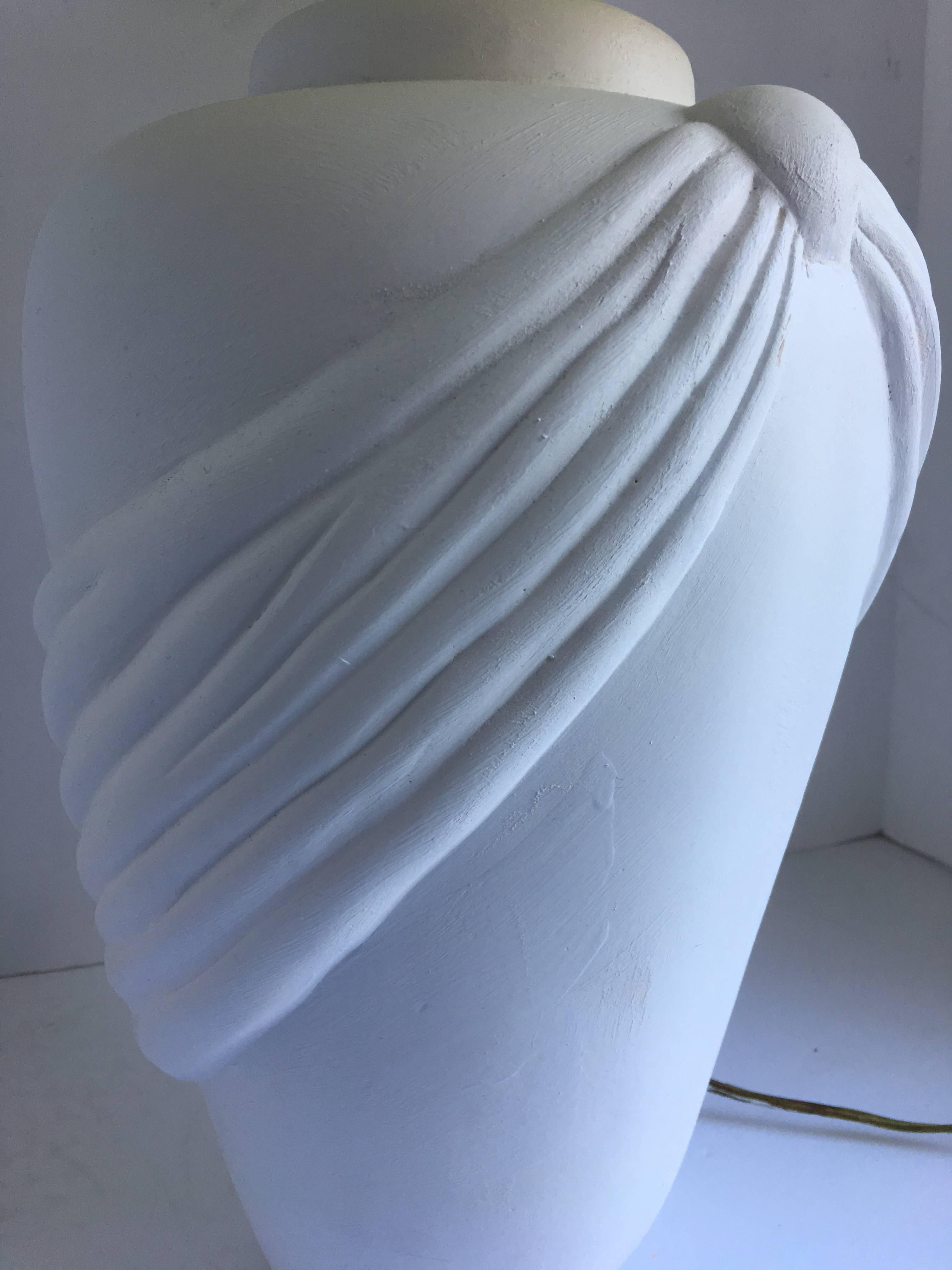 Hollywood Regency style plaster, like white matte ceramic table lamp featuring a dimensional drape design. In the style of John Dickinson. Lampshade not included.

Measures: 19.5 H to socket.
27 H to finial.
