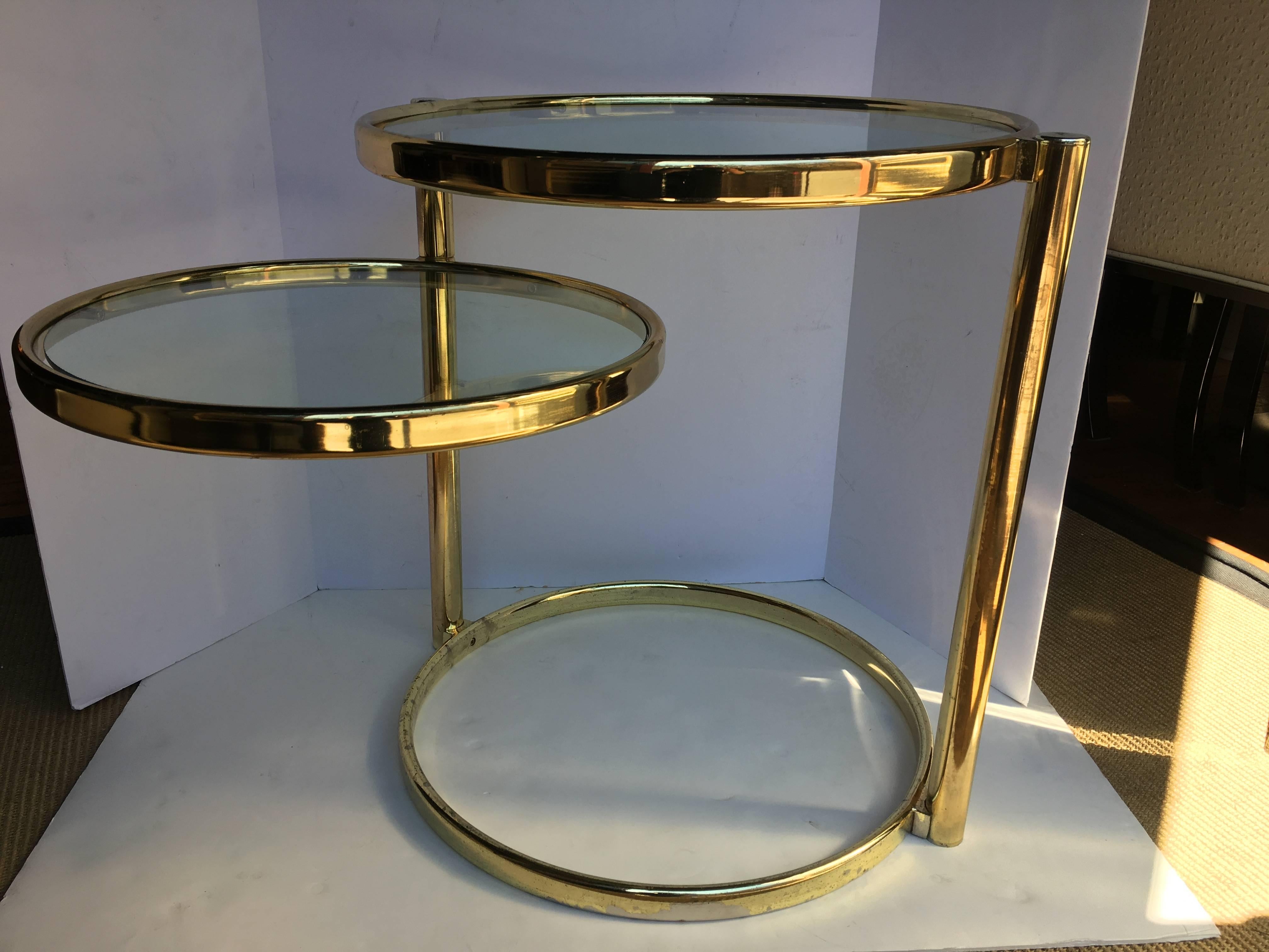 Mid-Century Modern two-tier articulating swivel brass accent or side table. 
Tubular brass plated frame features two removable round clear glass inserts. Top tier is stationary while the second round tier can swivel to desired position. 
Table can