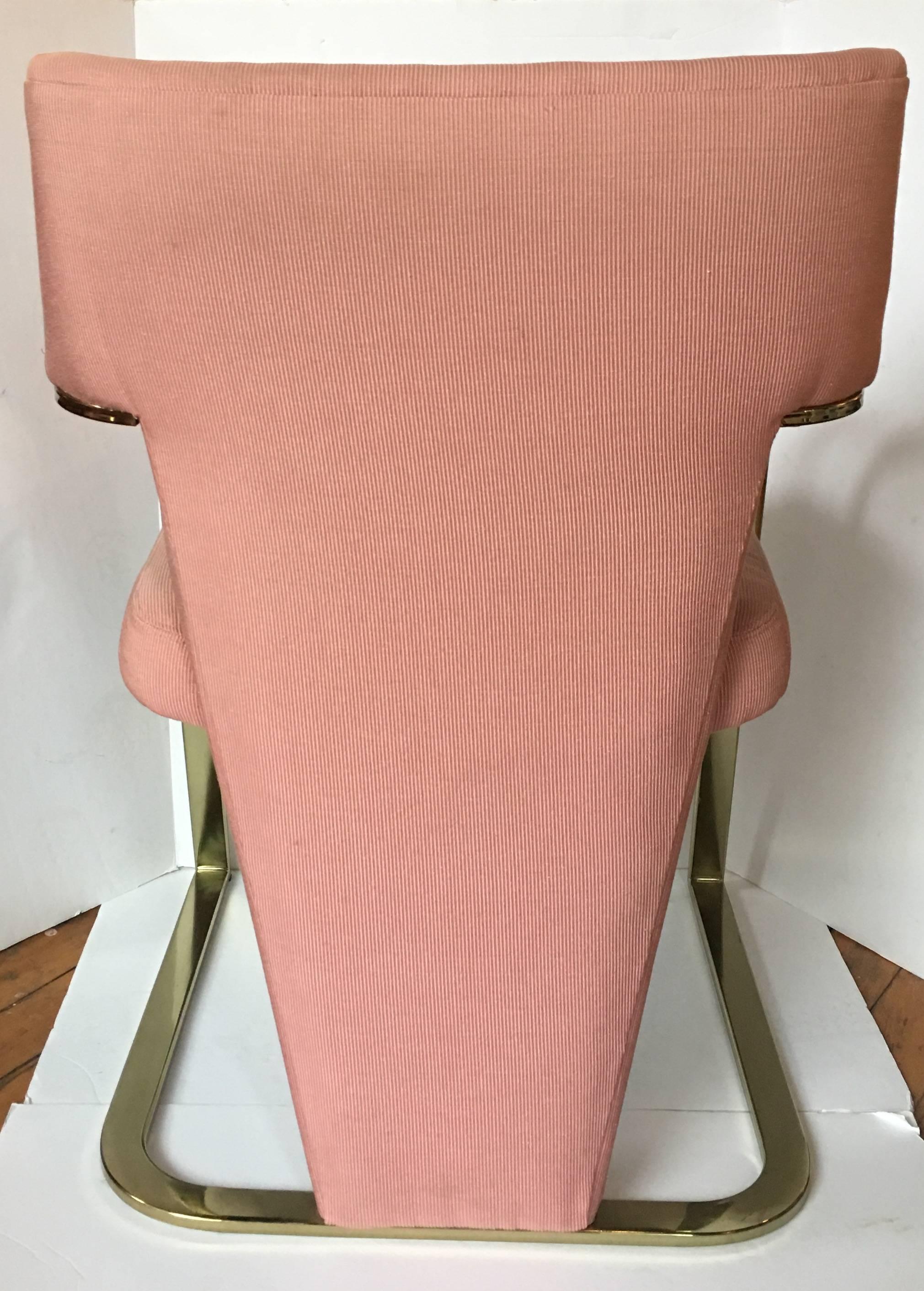 Set of four Hollywood Regency style brass plated metal arm chairs designed by Randy Culler for Carson's of High Point. Chairs feature sculptural modern cantilevered flat bar frames with original pink upholstery. Chairs have been stored since the