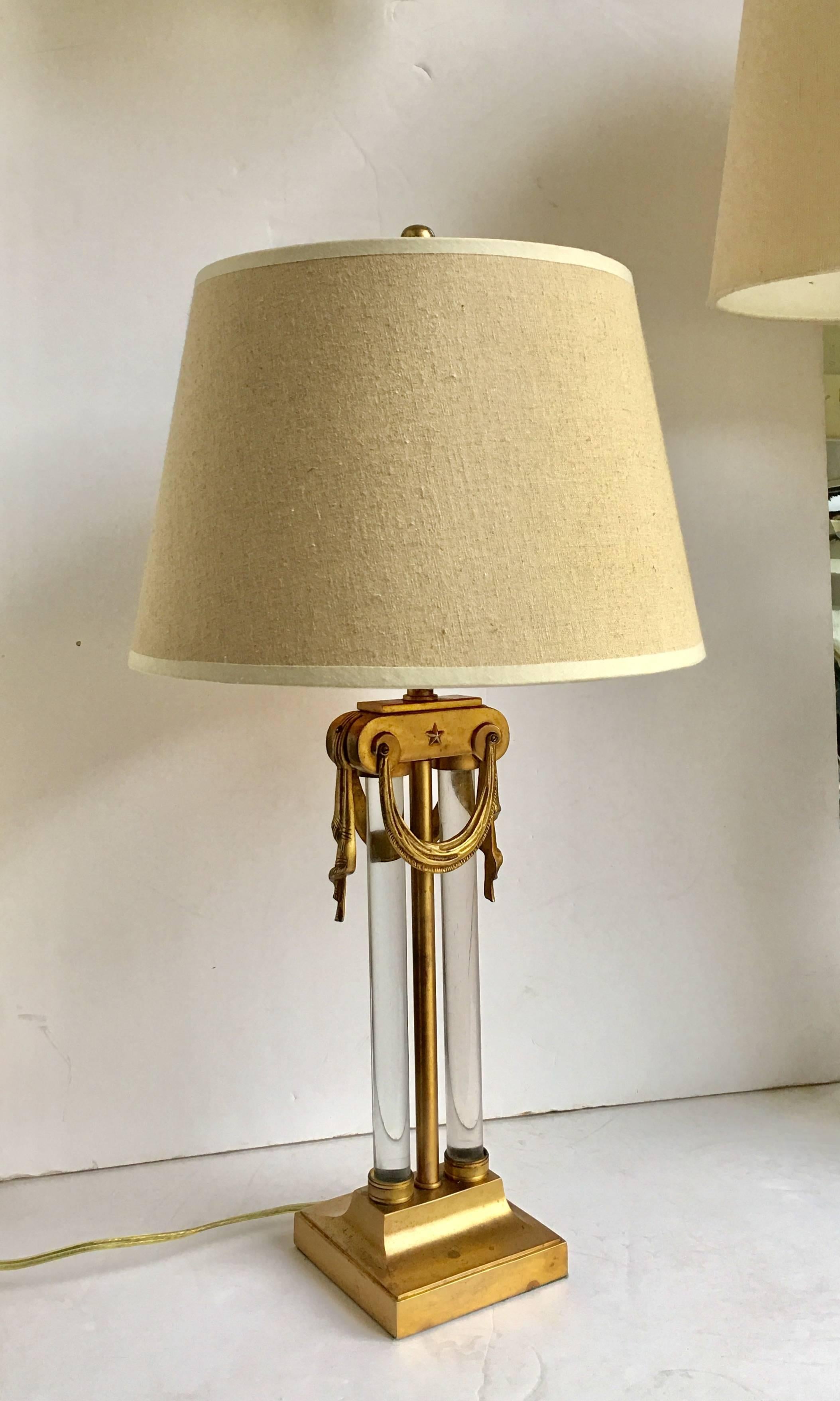 Neoclassical style brass and glass table lamp by Gilbert Rohde for Mutual Sunset Lamp Company. Lamp features heavy glass tubular rods, draped swags, and star motifs. Original harp and finial.  Lampshade NOT included.