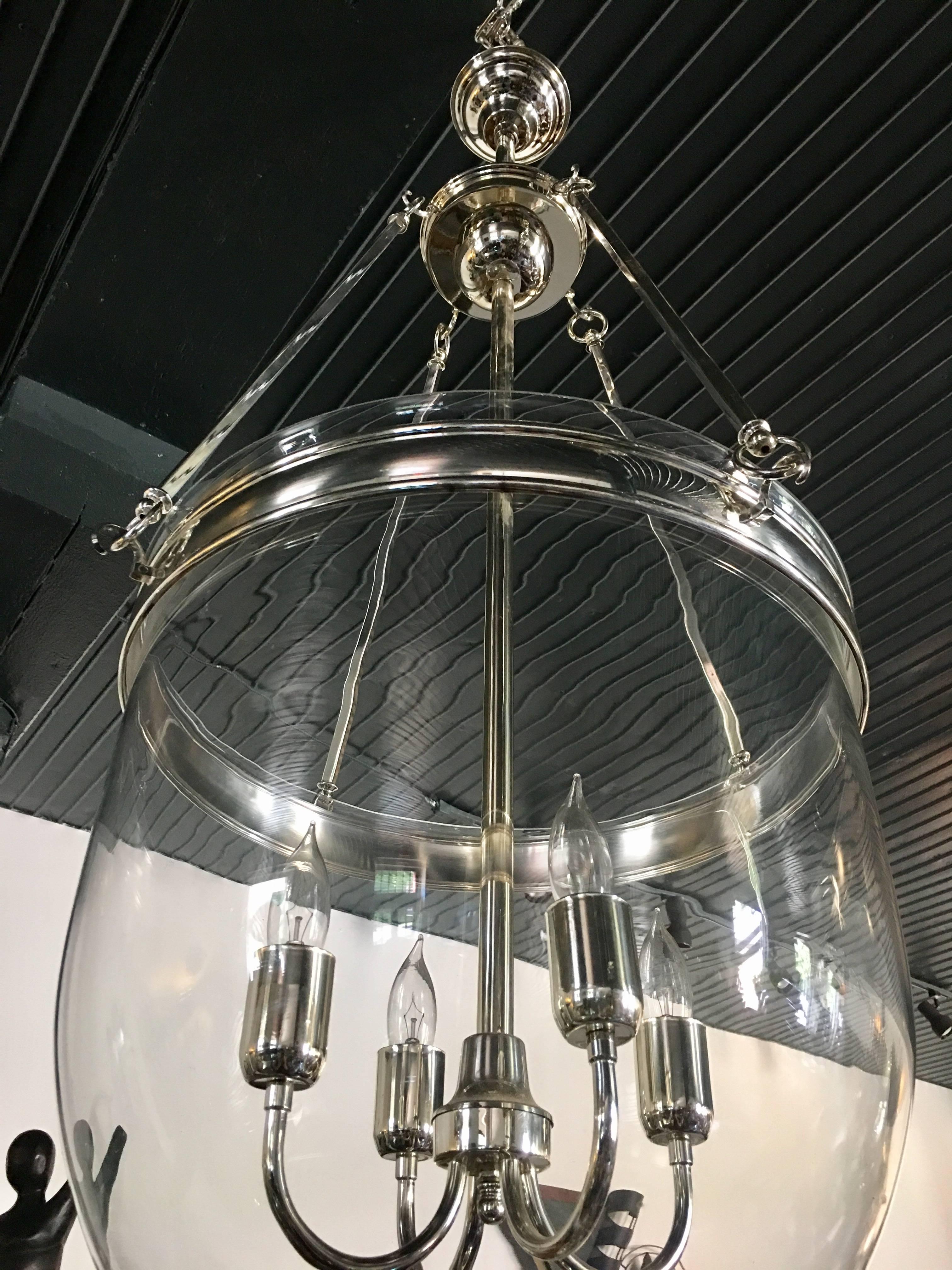 Large glass and polished chrome hurricane dome pendant light fixture. Removable clear glass bell jar is suspended from four square rods. Centre holds four standard base candle bulbs.

Measure: Height is adjustable. Length of fixture from bottom