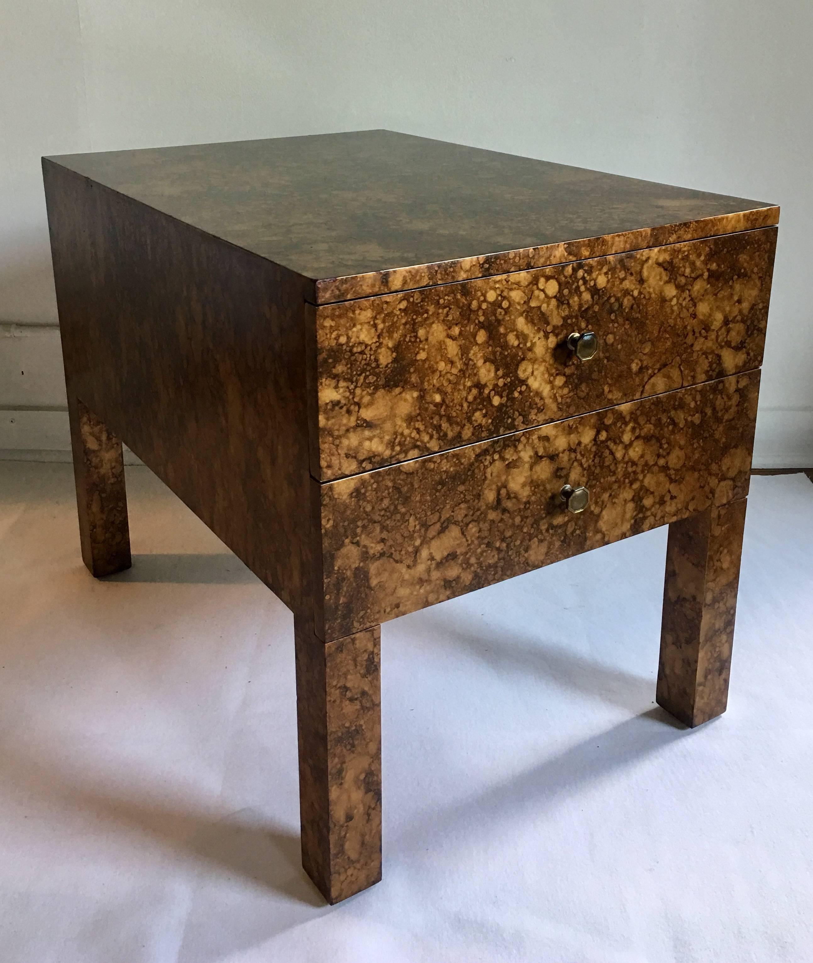 Mid-Century Modern parsons style side or end table. This rectangular shaped two drawer wood accent table features a hand painted faux tortoise shell or oil drip finish. Original brass hardware. A solid and heavy piece. In the style of Billy Haines