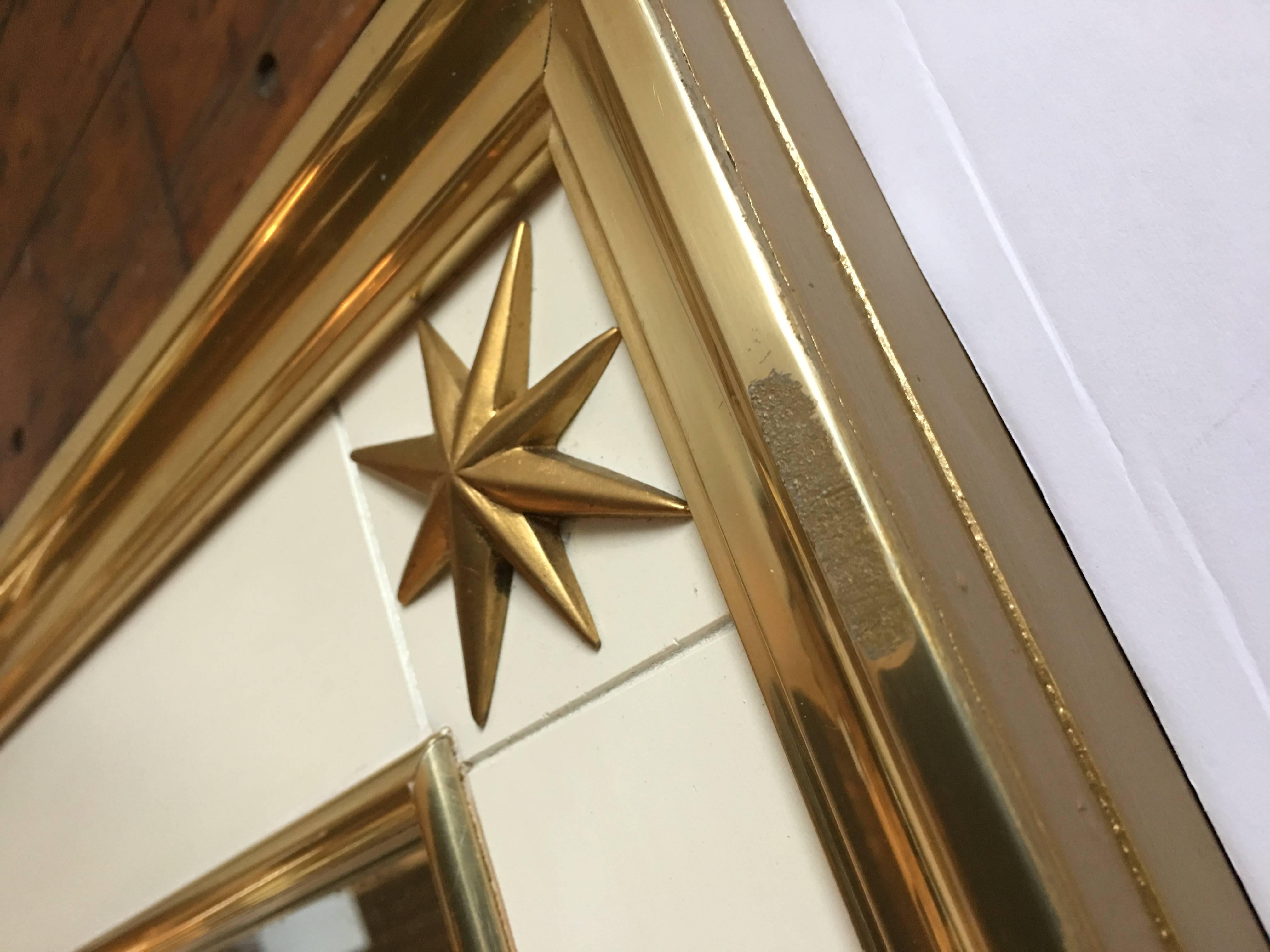 Large rectangular Mid-Century Modern brass metal wrapped mirror with decorative brass stars. This Neoclassical style mirror was designed by Renzo Rutili for Johnson Furniture Company.  Solid wood frame features a cream painted finish and gold