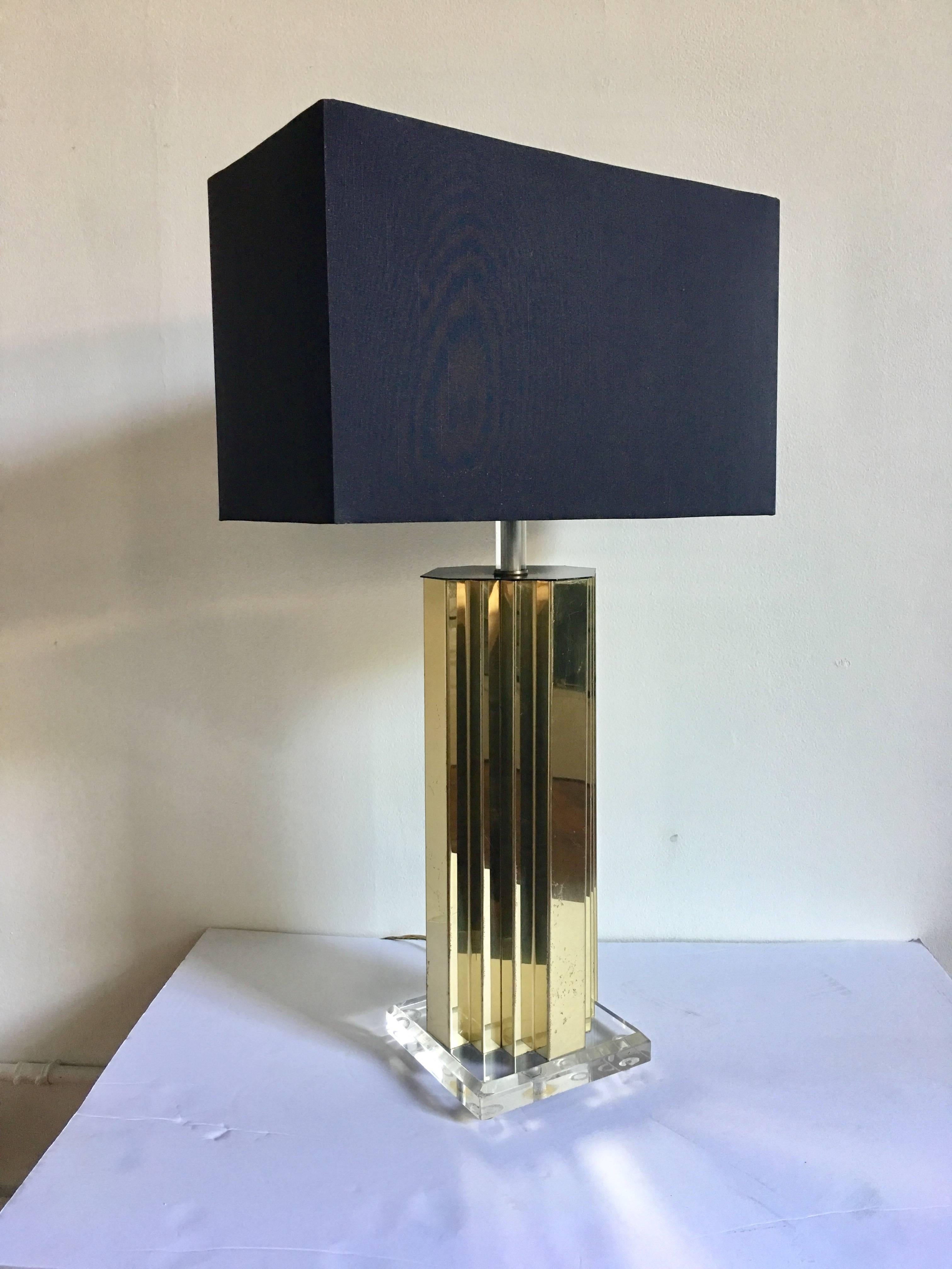 Glamorous Mid-Century Modern brass metal and Lucite table lamp. Base features a skyscraper form brass body mounted on a clear Lucite base.
In the style of Curtis Jere. Lampshade not included. 

Measures: Height to finial: 28.5 Inches.
Height to