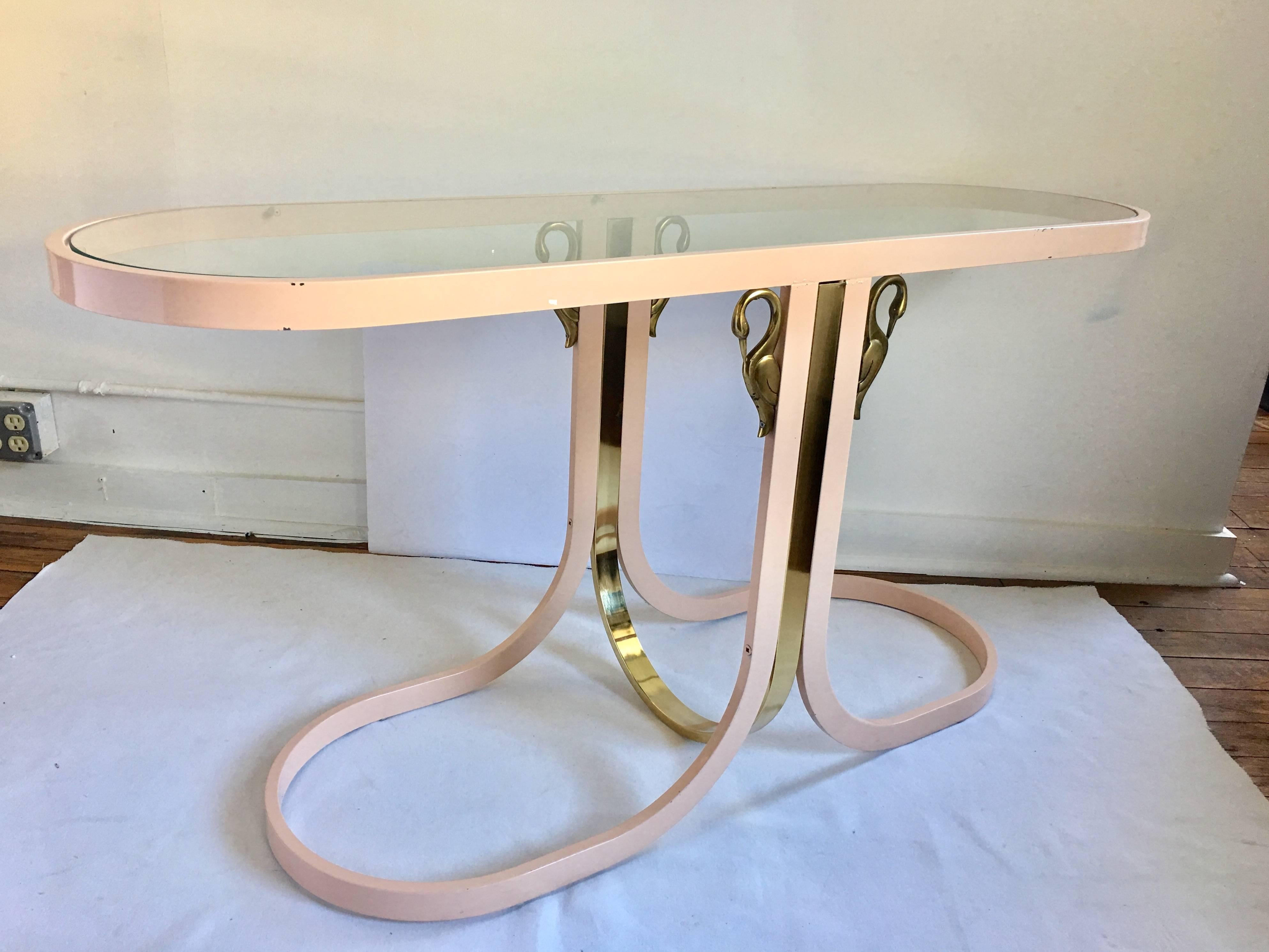 Modern brass and glass console sofa table by DIA, Design Institute America. Sculptural metal frame features original pale pink painted lacquered finish with a brass plated curved center support and decorative brass swan figures. Reovable clear glass