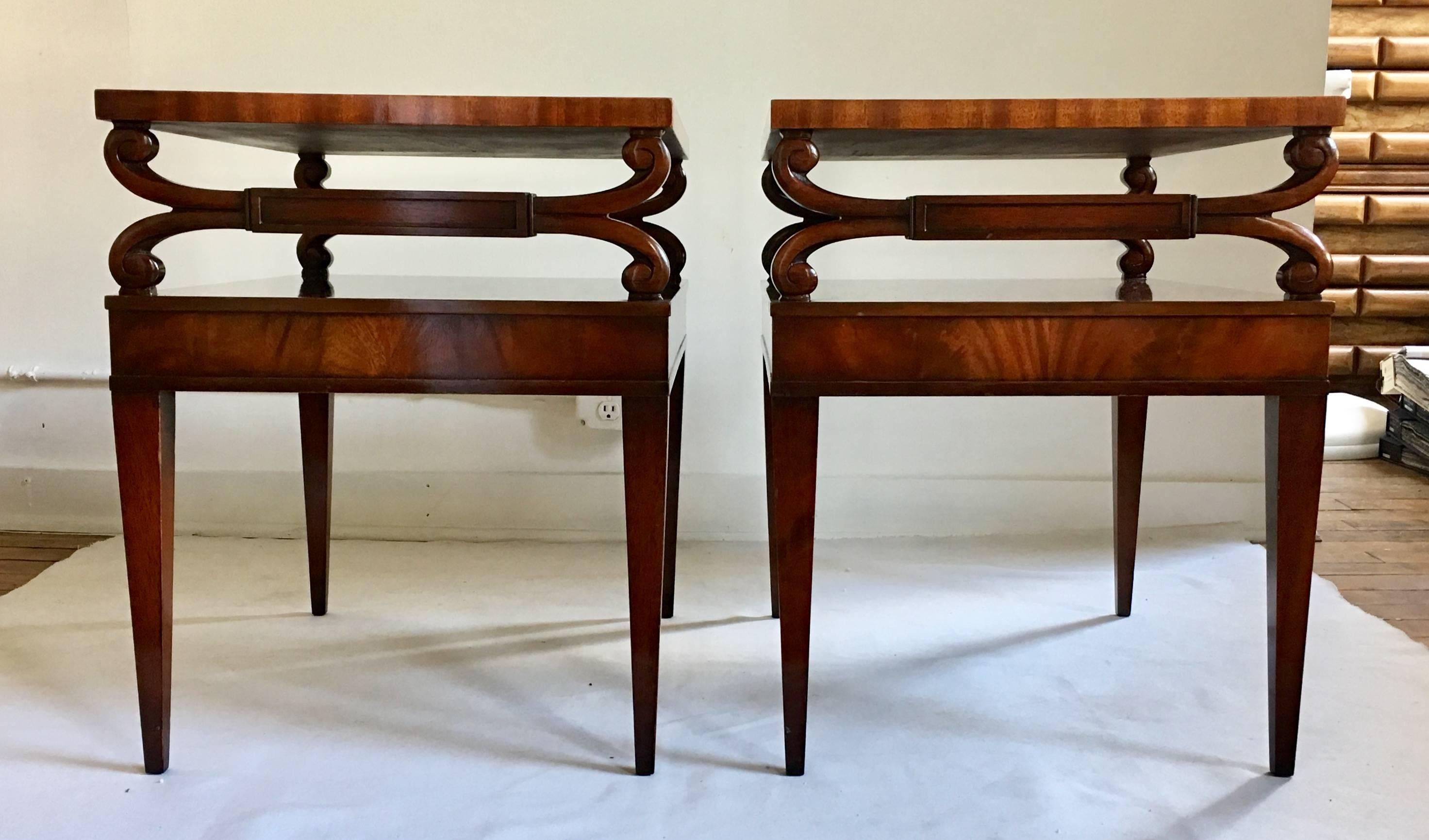 Midcentury Regency style two tier side tables from Weiman's Heirloom collection. Mahogany wood frames feature carved scroll details, gold scribed brown leather tops, and tapered legs. Stamped 