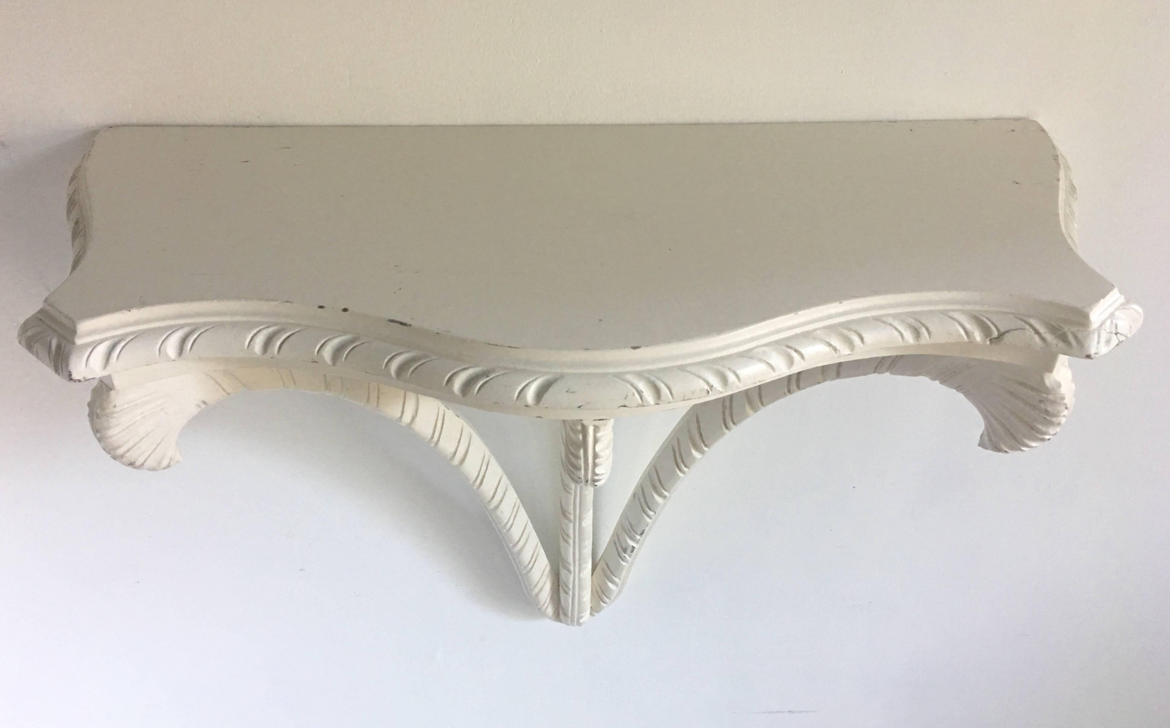 Large Mid-Century Hollywood Regency style wall-mounted console shelf or bracket. Sculptural carved mahogany wood features acanthus leaf or plum design and painted white/cream finish. Nice size for a small entry or hallway and could also be used as